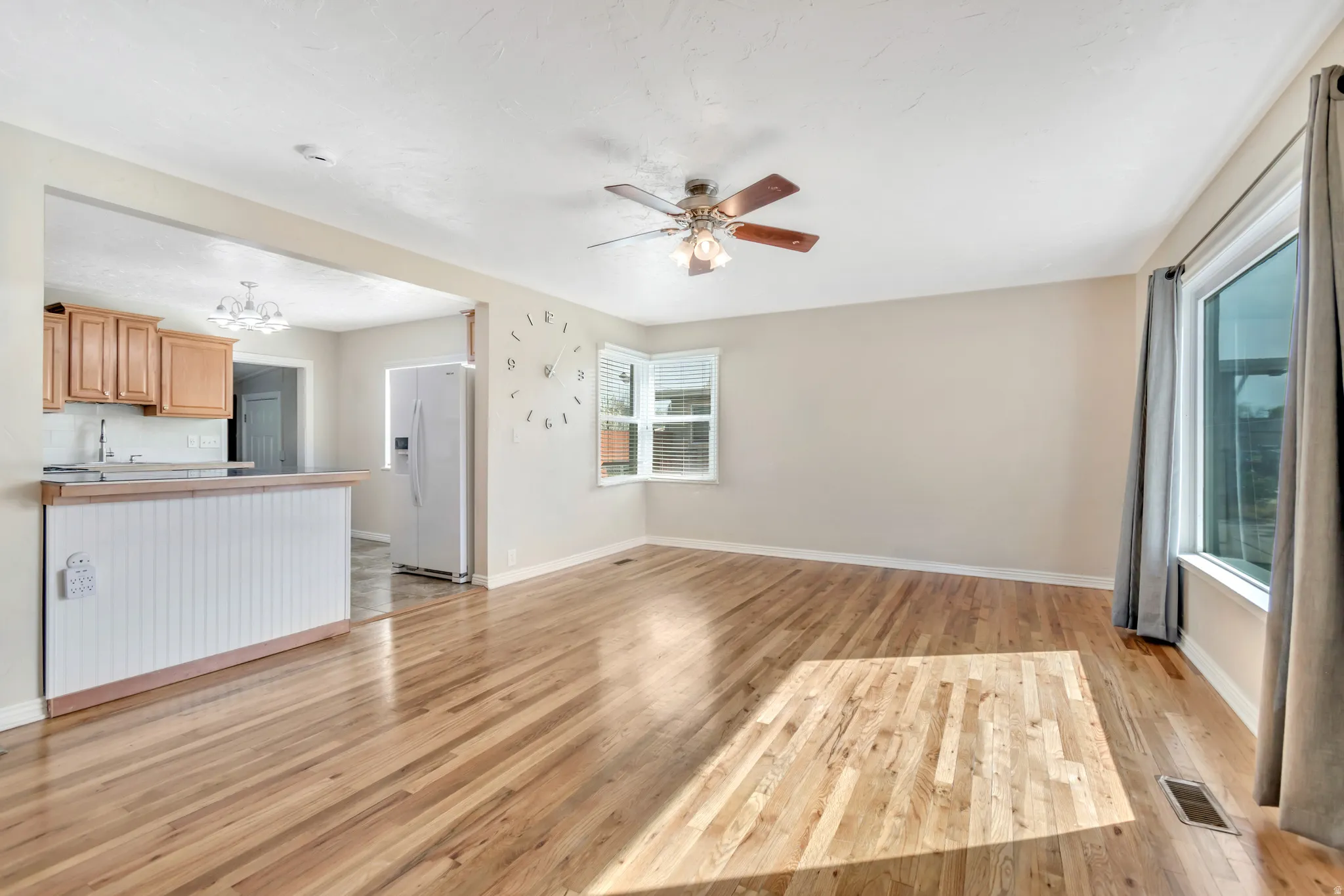 Unfurnished living room featuring a ceiling fan, a chandelier, and light wood finished floors