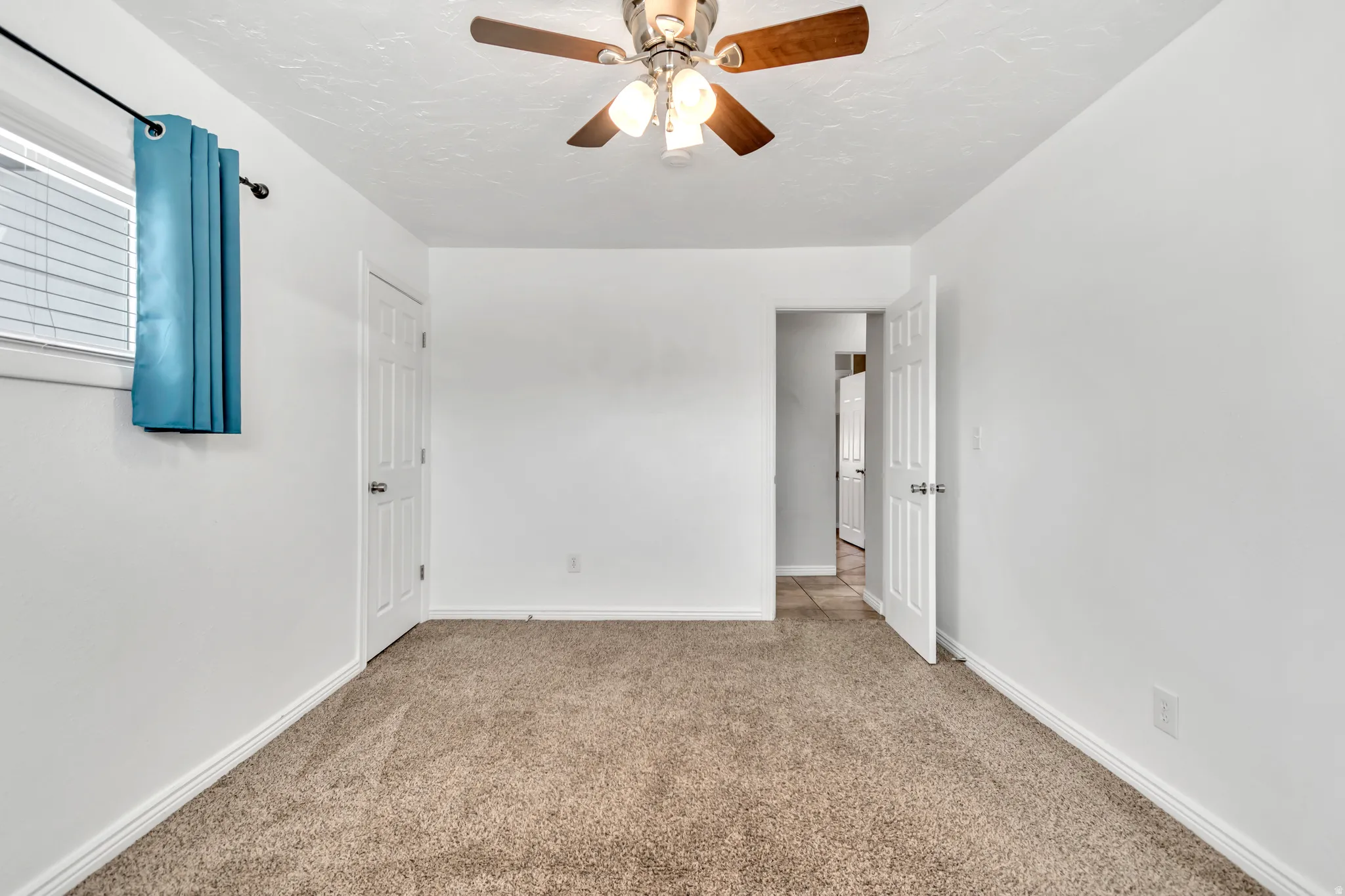 Unfurnished bedroom with light carpet and a ceiling fan