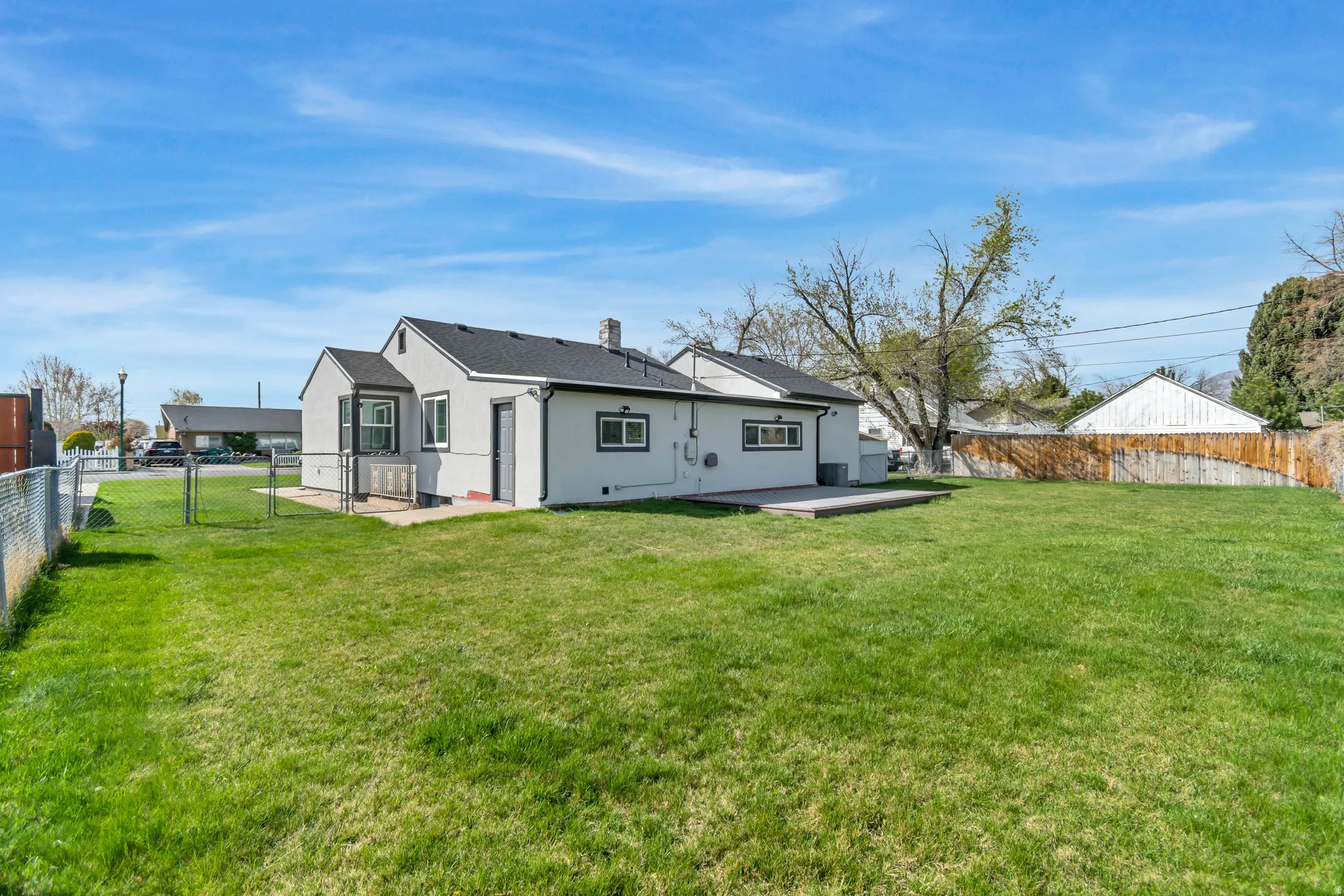 Rear view of property with a fenced backyard, a patio area, a chimney, stucco siding, and a gate