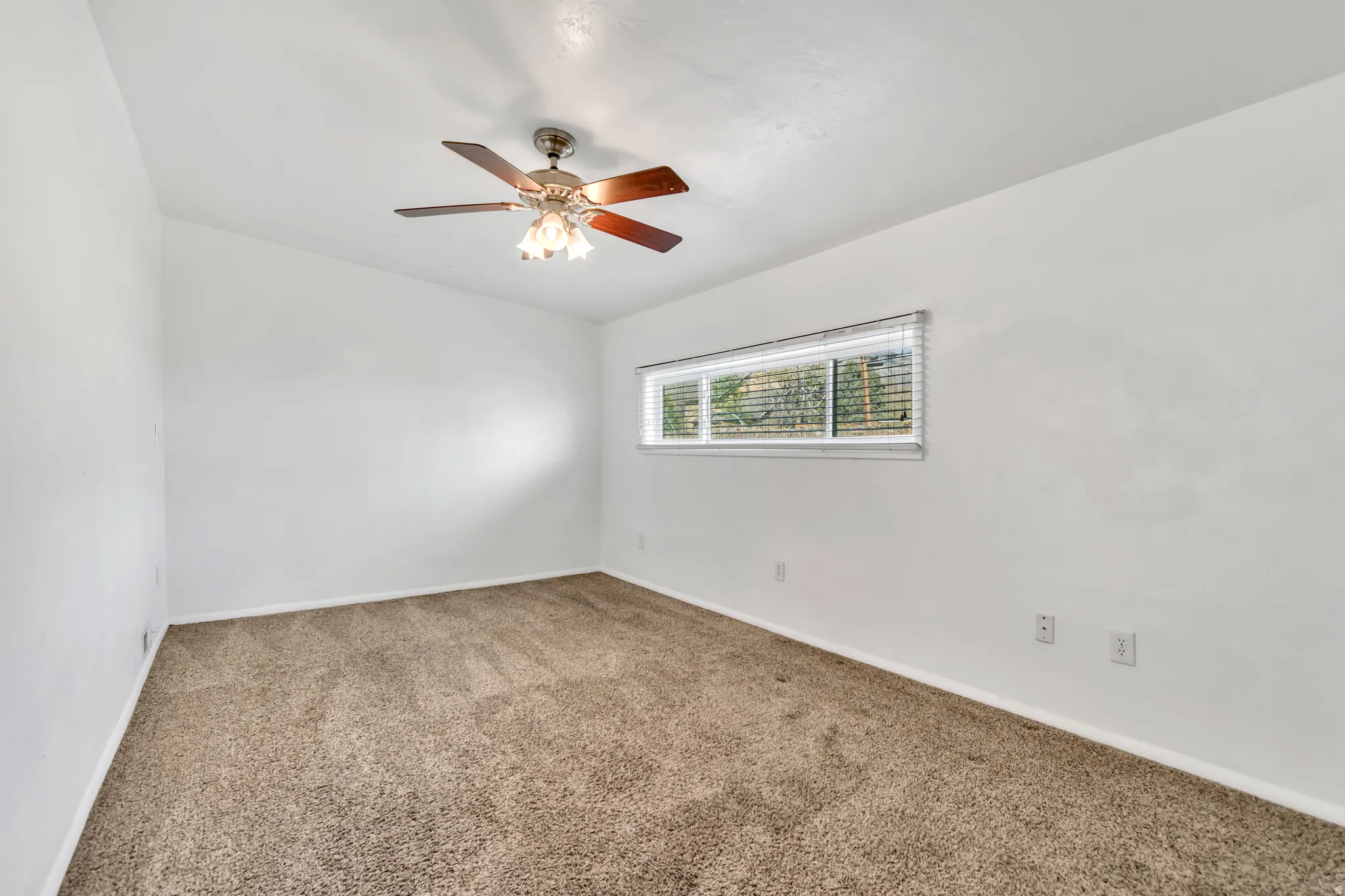 Empty room with carpet flooring and a ceiling fan