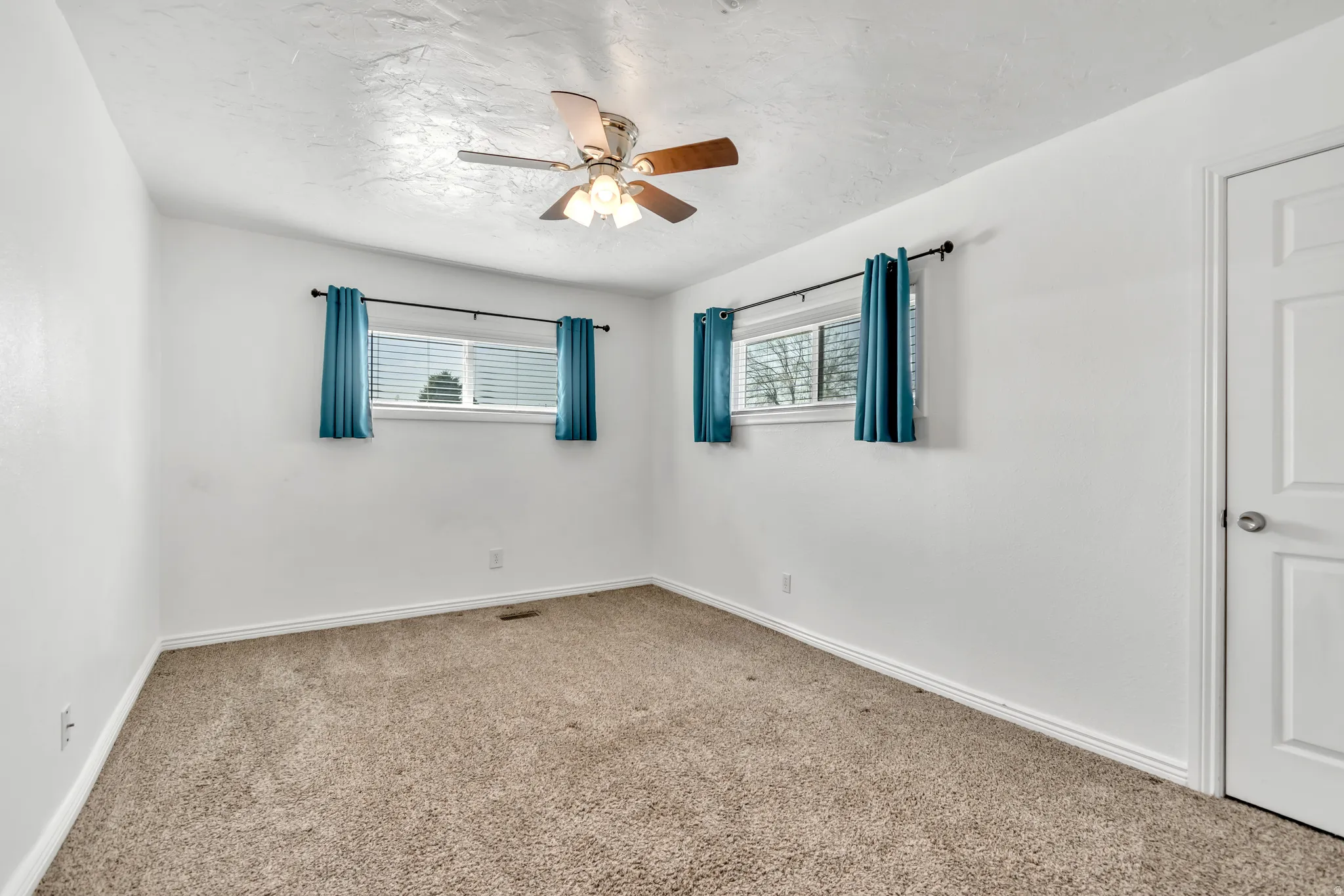 Carpeted empty room with ceiling fan and baseboards