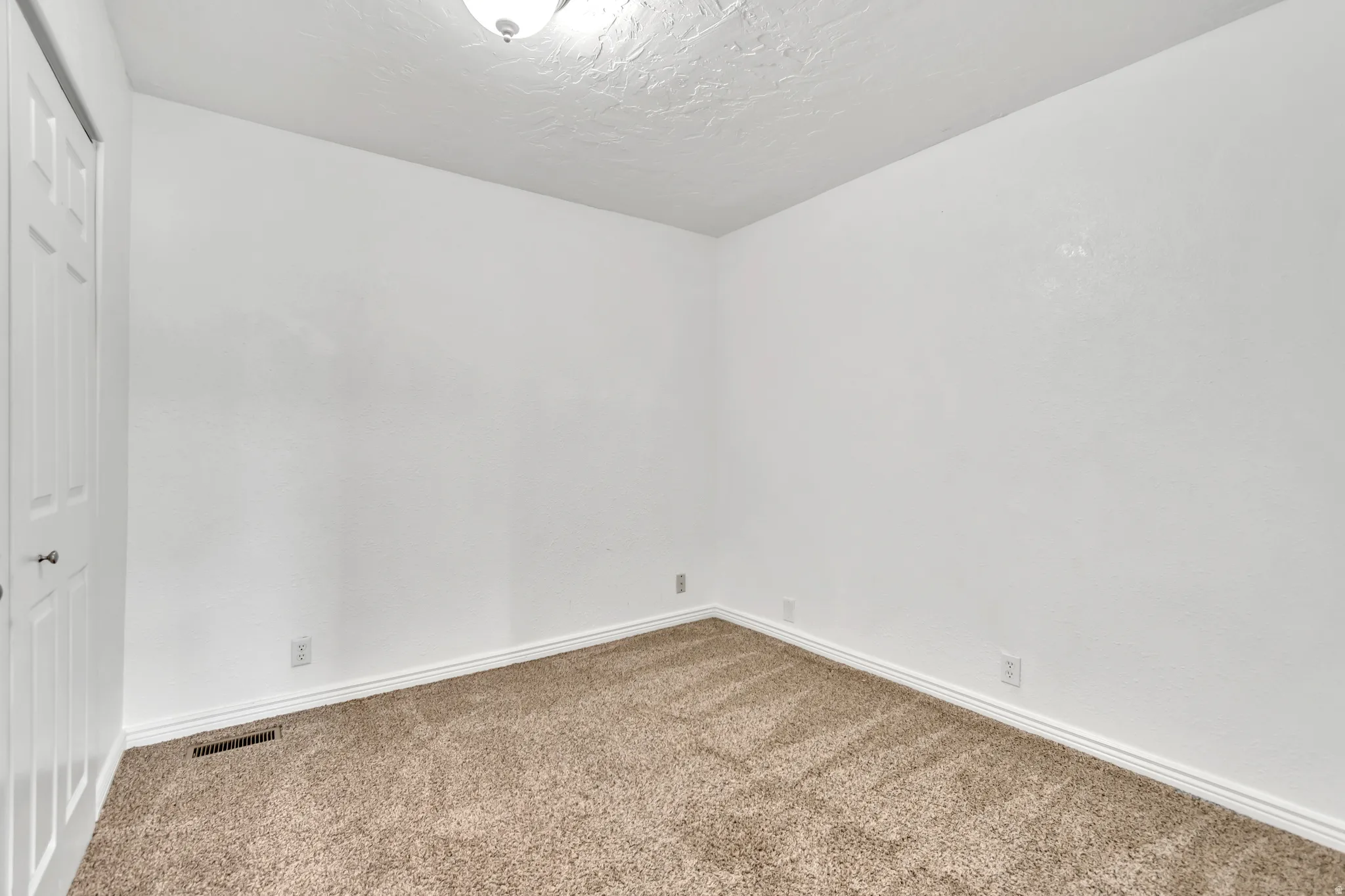 Carpeted spare room with baseboards and a textured ceiling