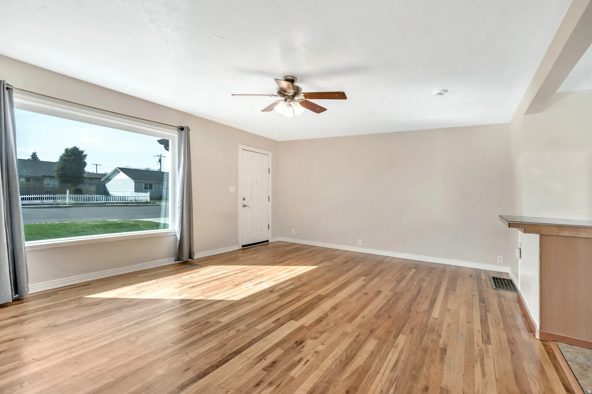 Unfurnished living room with light wood-style floors and a ceiling fan