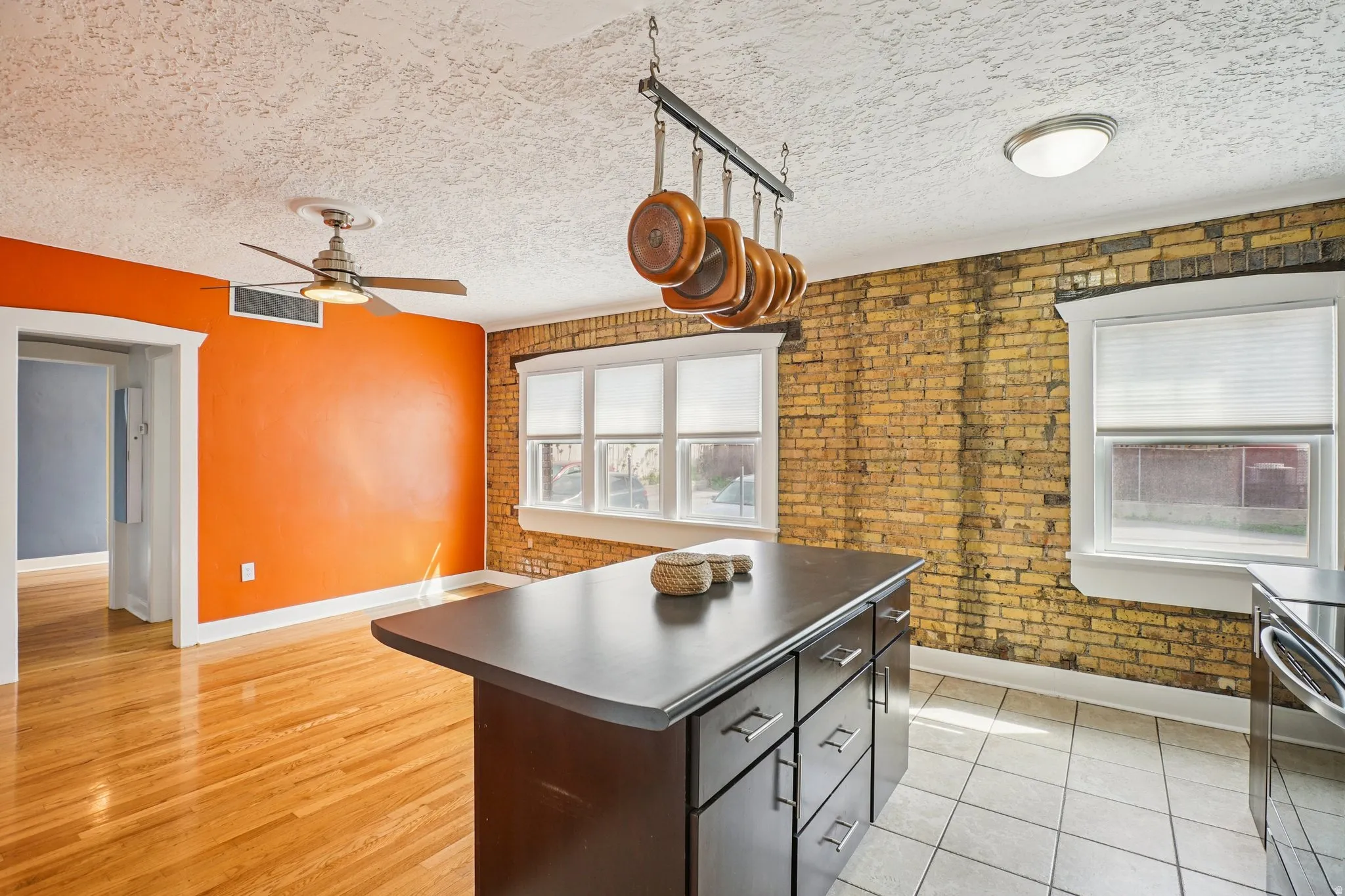 Kitchen with brick wall, dark countertops, stainless steel stove, a kitchen island, and a textured ceiling