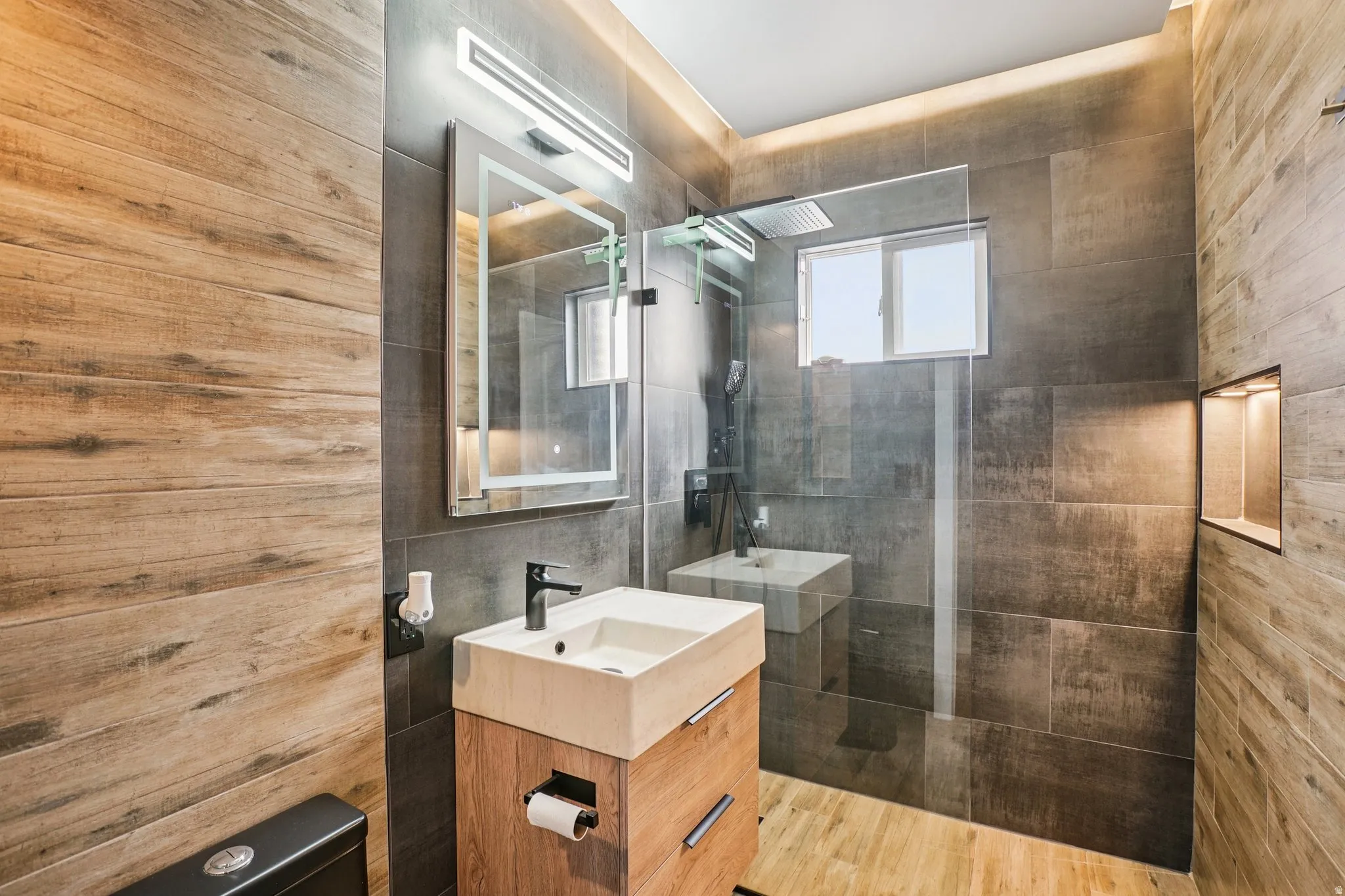 Bathroom with vanity, walk in shower, and tile walls
