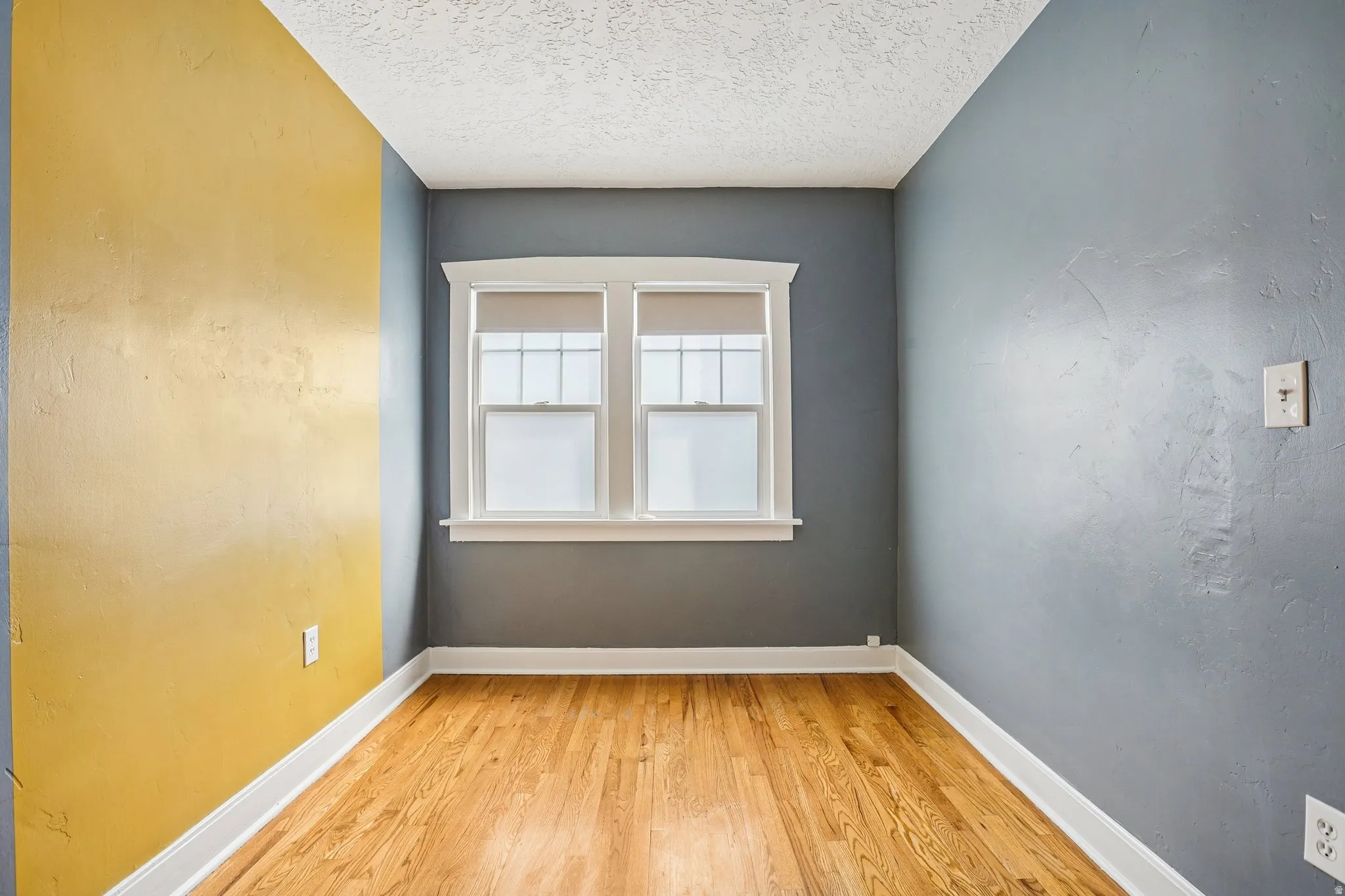 Spare room with light wood finished floors and a textured ceiling