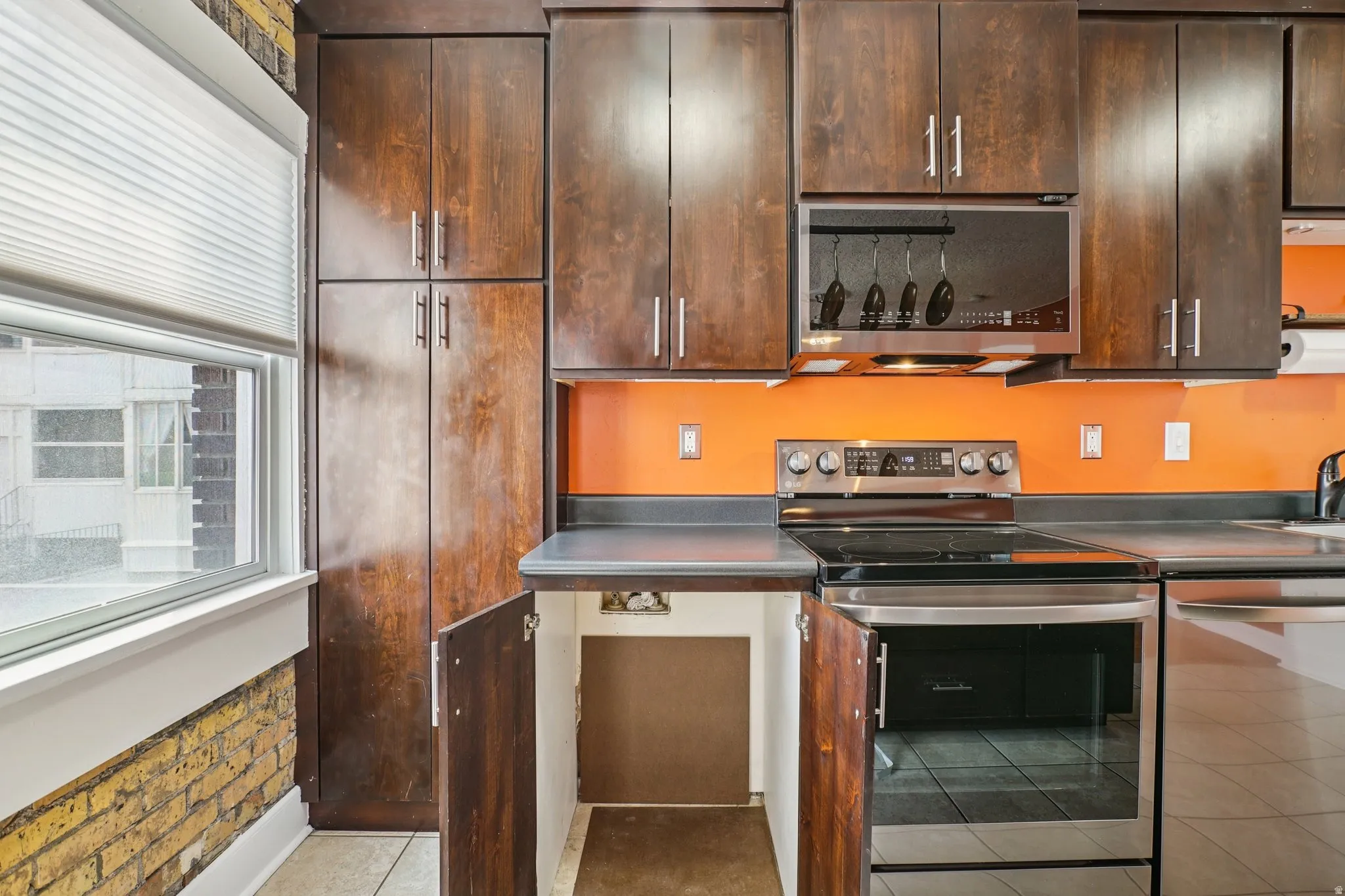 Kitchen featuring stainless steel appliances, dark wood finish cabinetry, and light tile patterned floors
