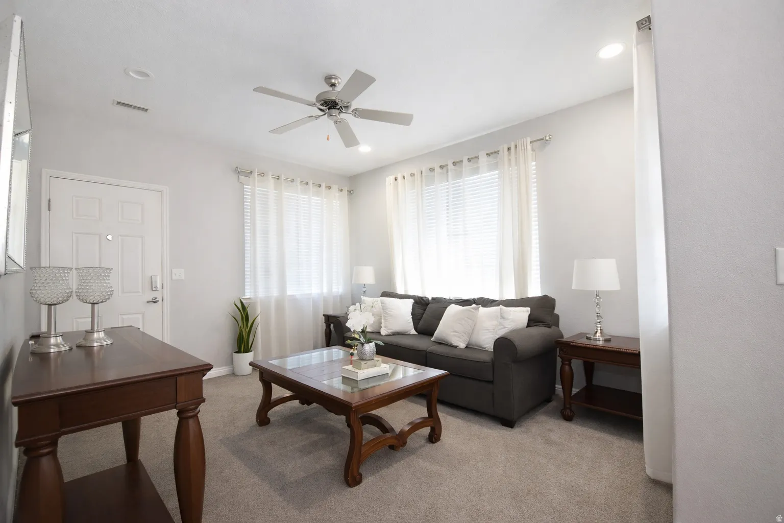 Living area with a ceiling fan and light colored carpet