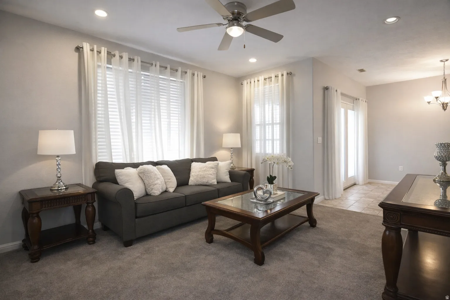 Carpeted living room featuring a ceiling fan and suspended lighting