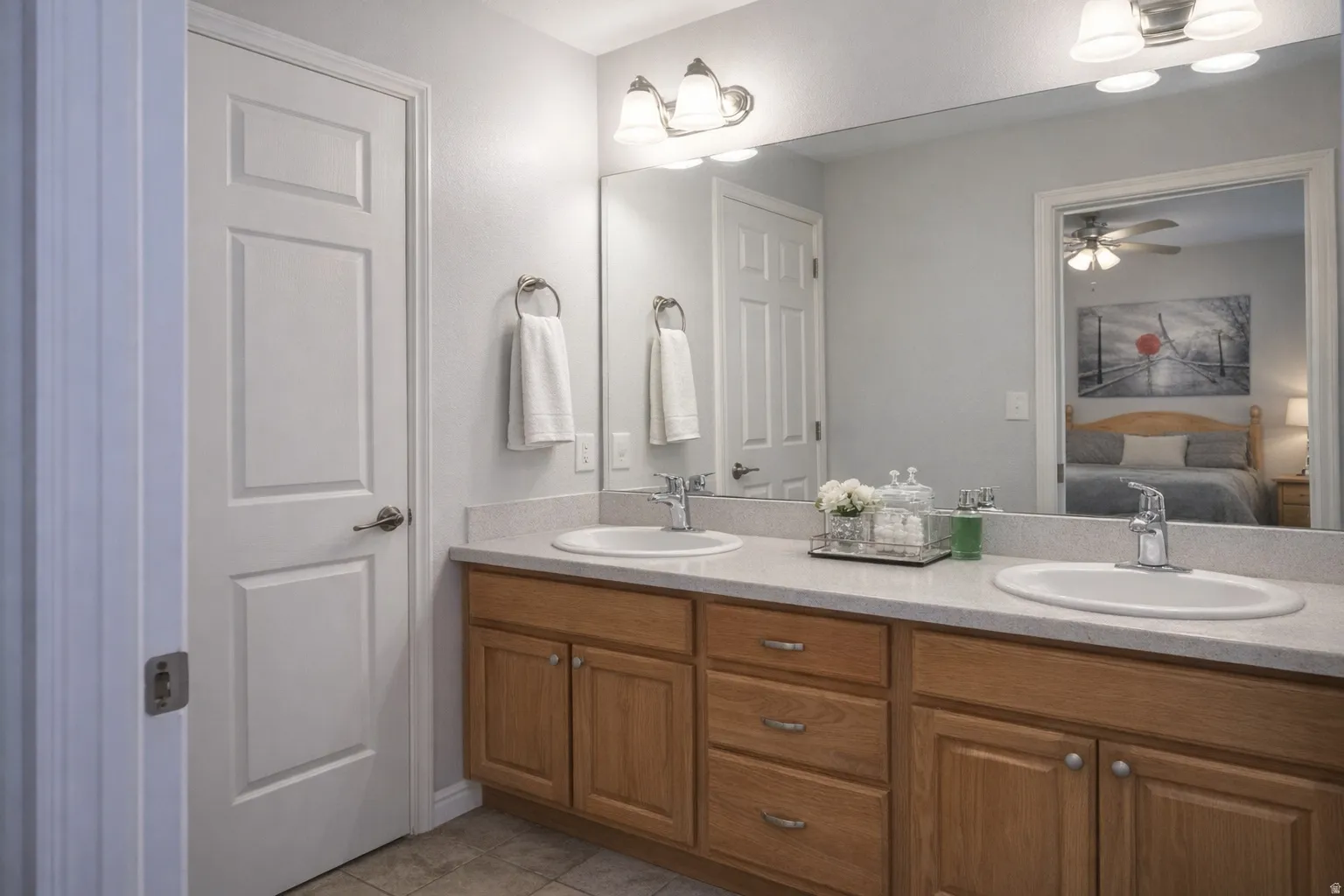 Bathroom featuring ensuite bath, double vanity, a ceiling fan, and light tile patterned floors