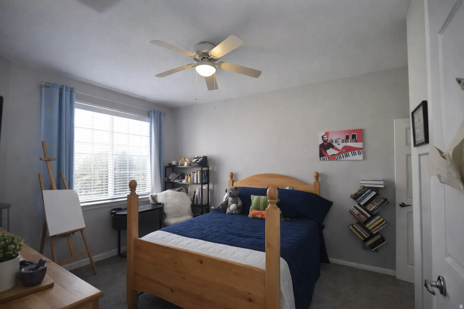 Bedroom with a ceiling fan and dark colored carpet