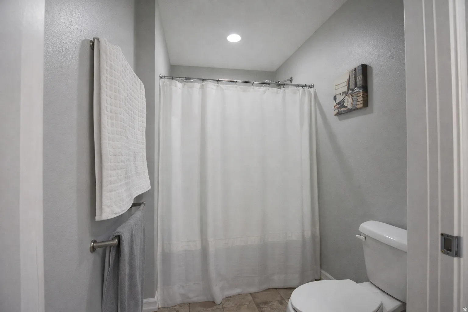 Full bathroom featuring curtained shower and a textured wall