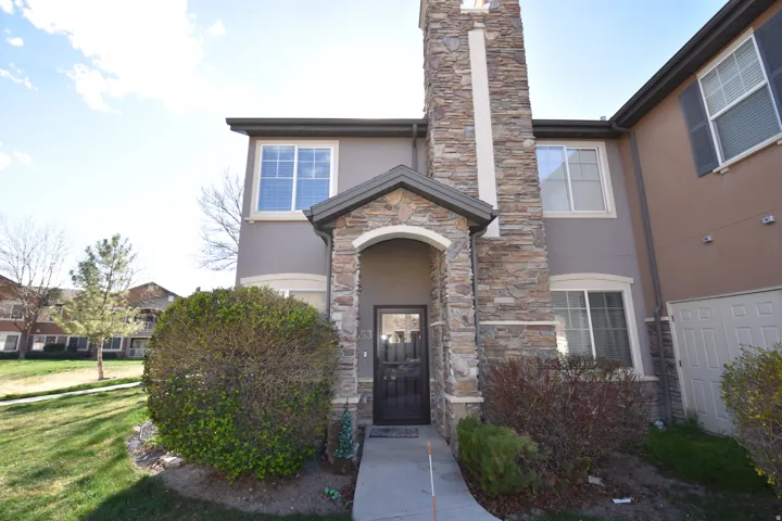 View of front of home with stucco siding, stone siding, a front lawn, and a chimney