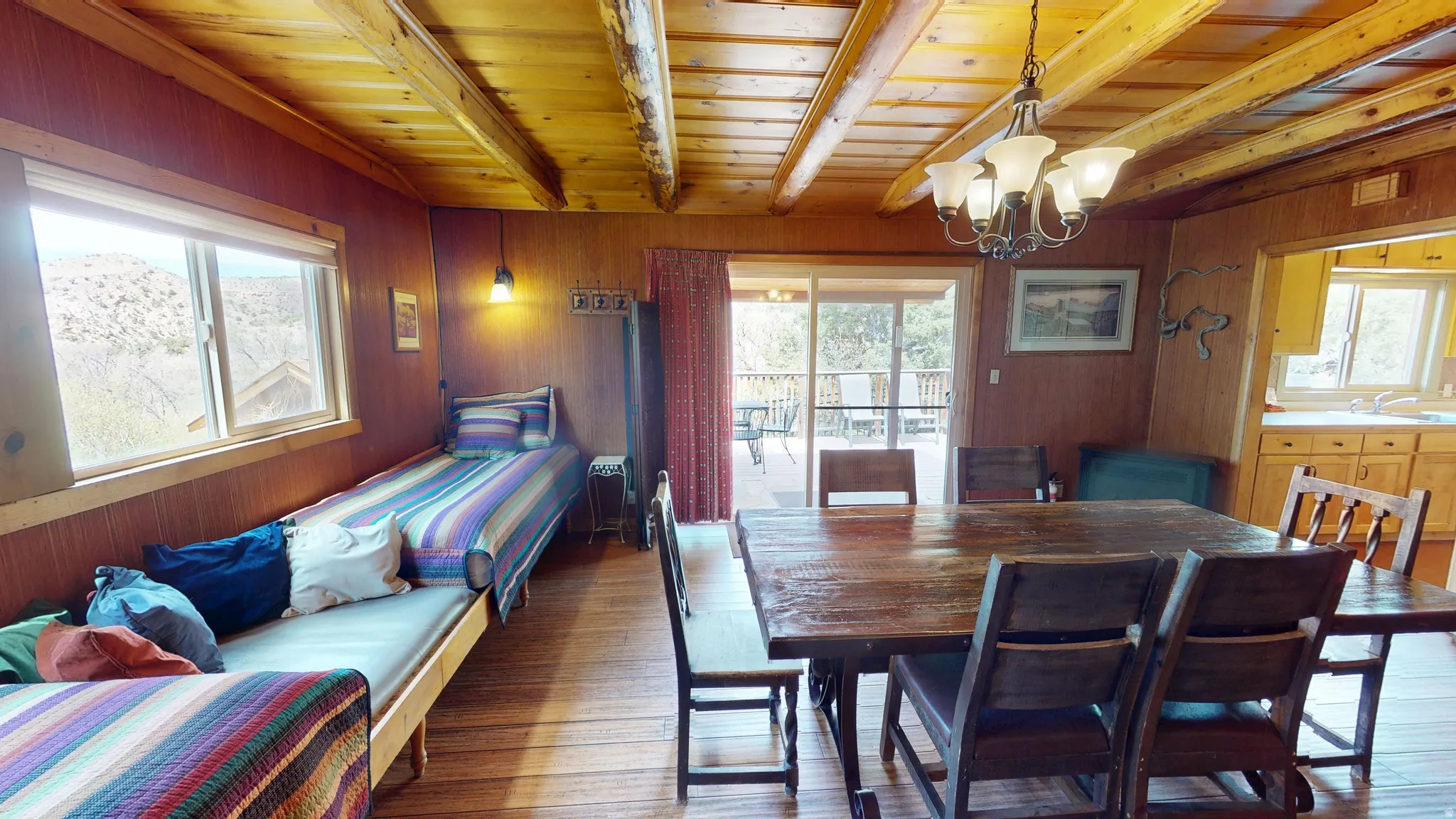 Dining room featuring wooden walls, wood finished floors, suspended lighting, and a wooden ceiling with exposed beams