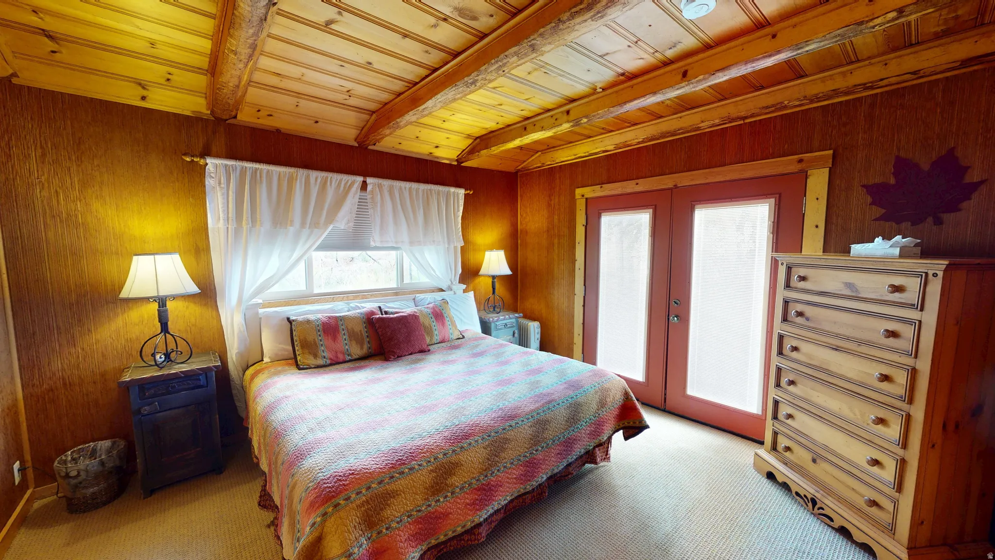 Bedroom featuring french doors, light colored carpet, wooden walls, and a wood ceiling with exposed beams