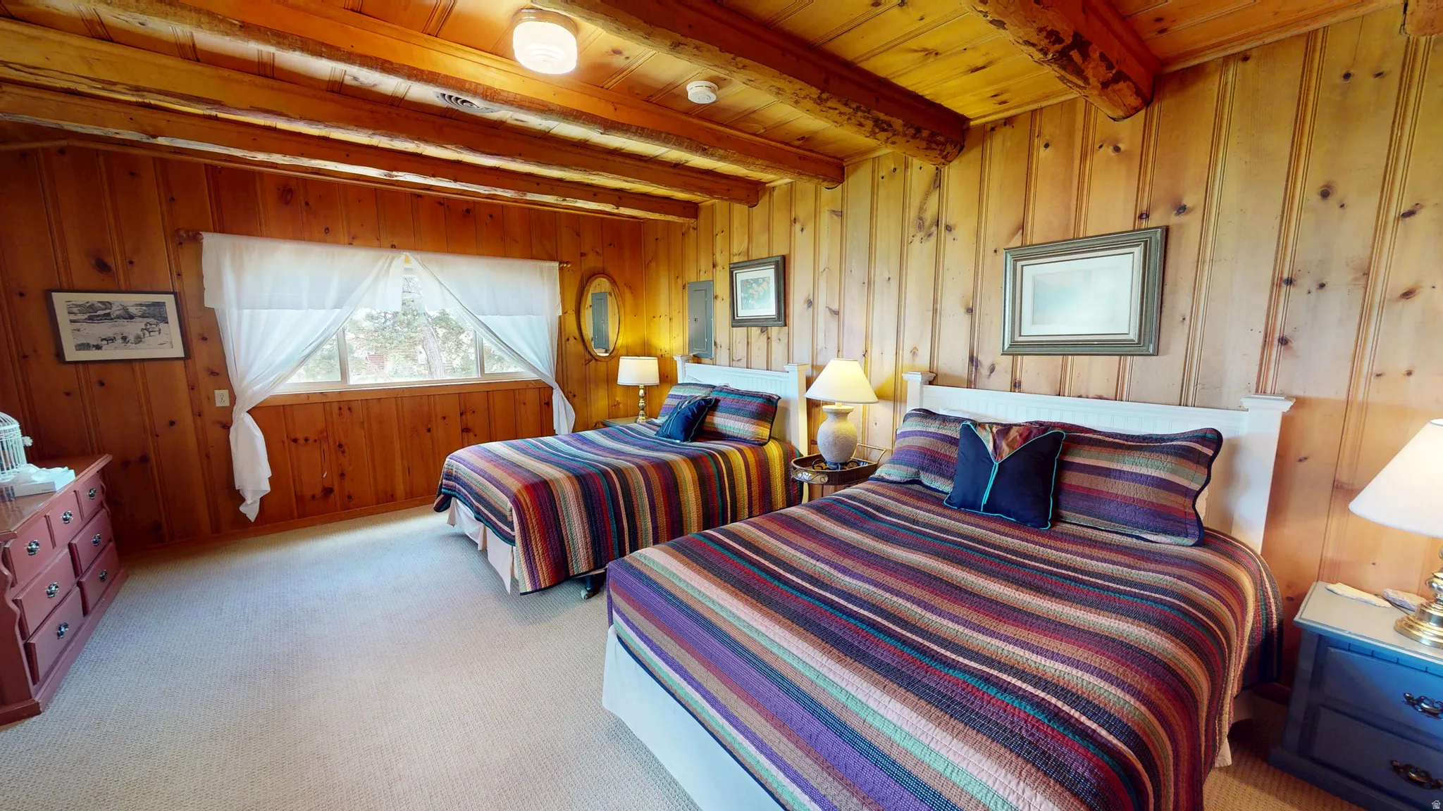 Bedroom with light colored carpet, wooden walls, a wooden ceiling with exposed beams, and electric panel