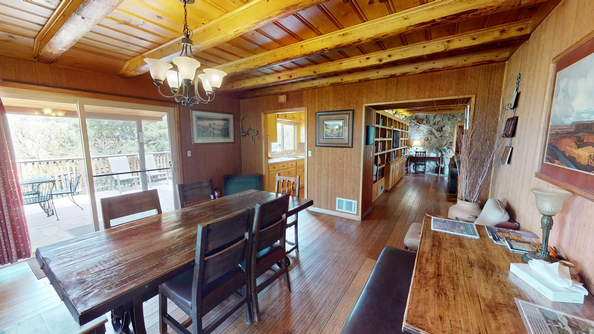 Dining room with wooden walls, dark wood-style flooring, suspended lighting, and a wood ceiling with exposed beams