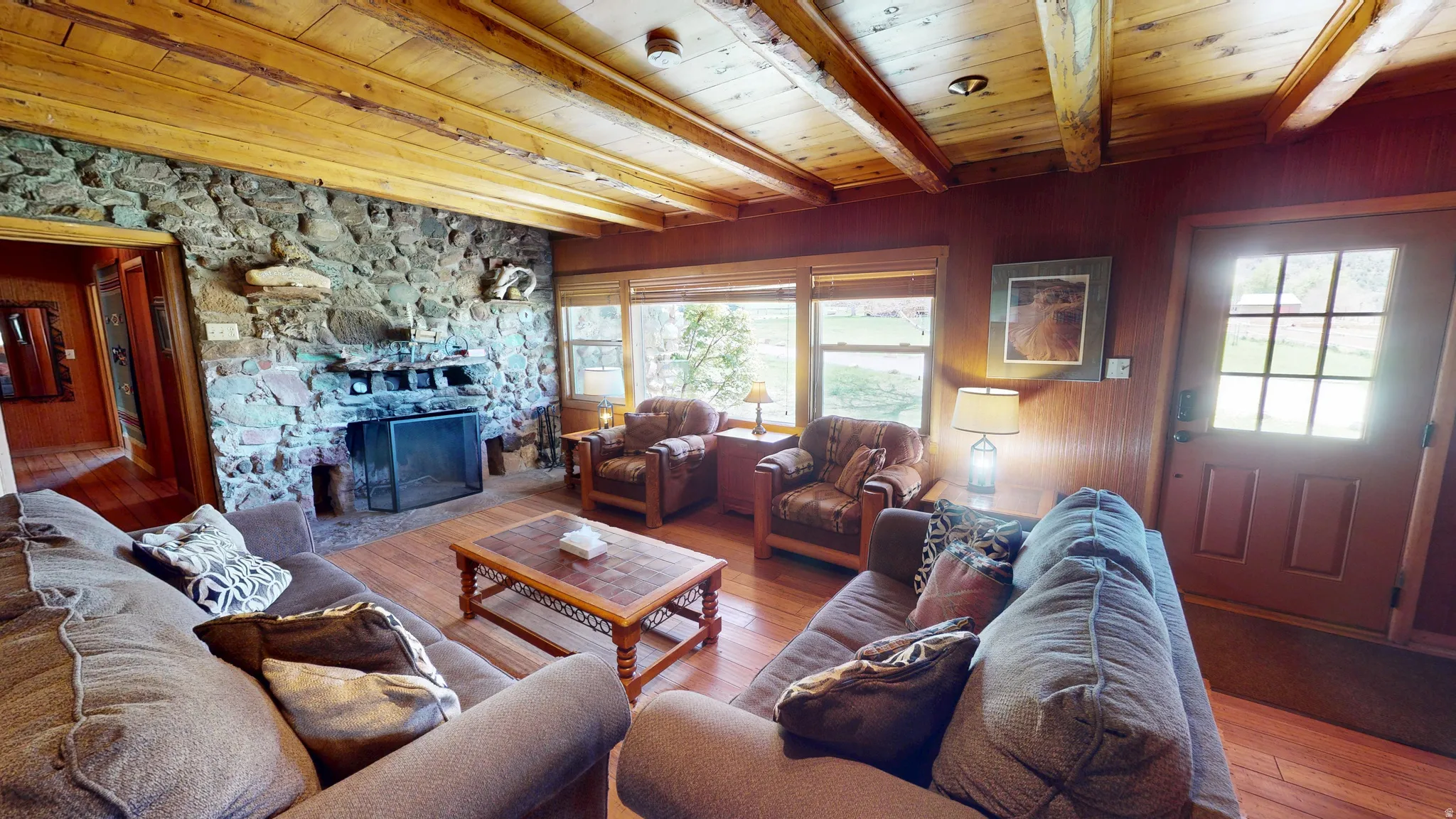Living room featuring hardwood / wood-style floors, a fireplace, and a wooden ceiling with exposed beams