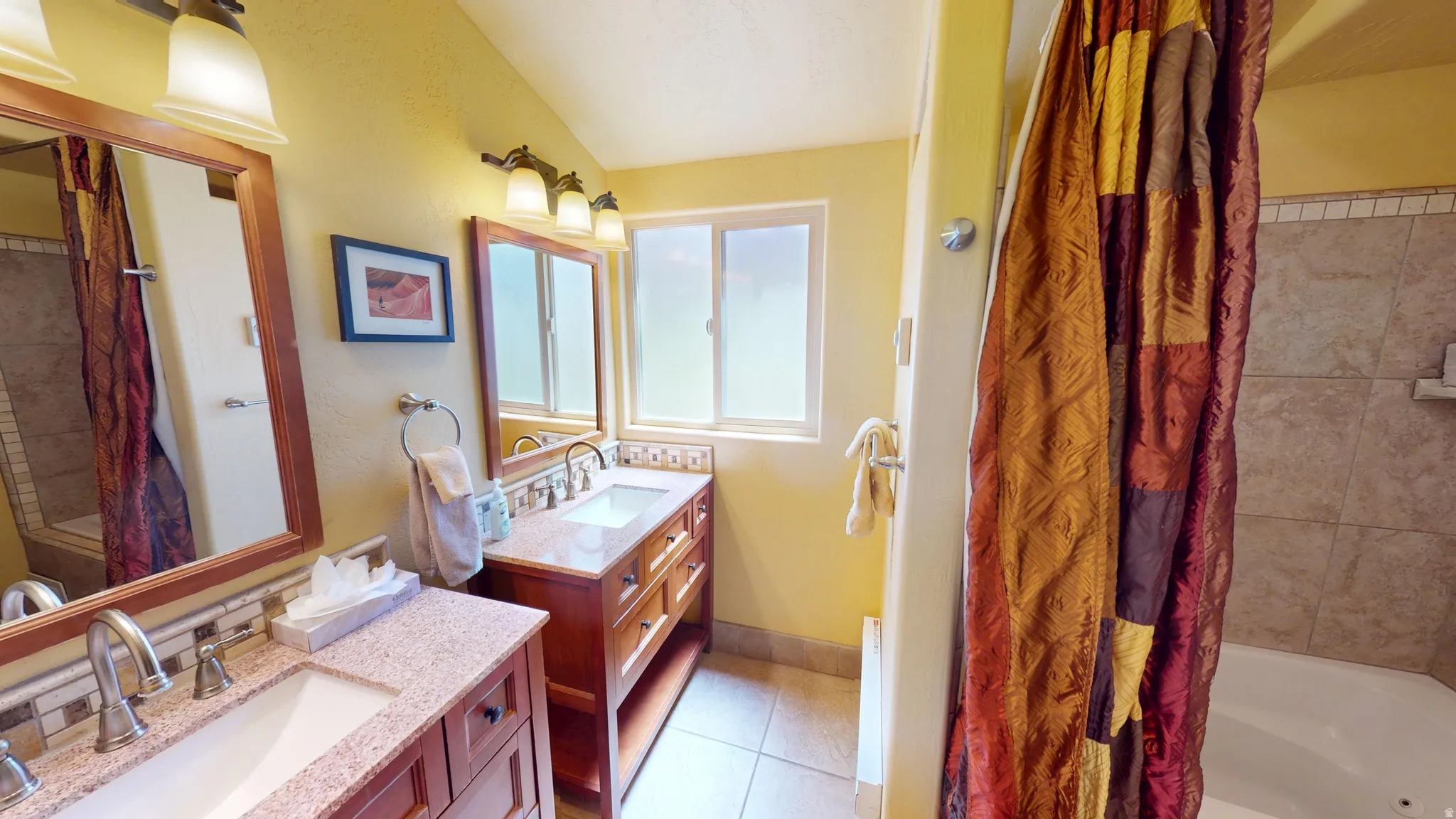 Full bath with two vanities, shower / tub combo with curtain, and light tile patterned floors