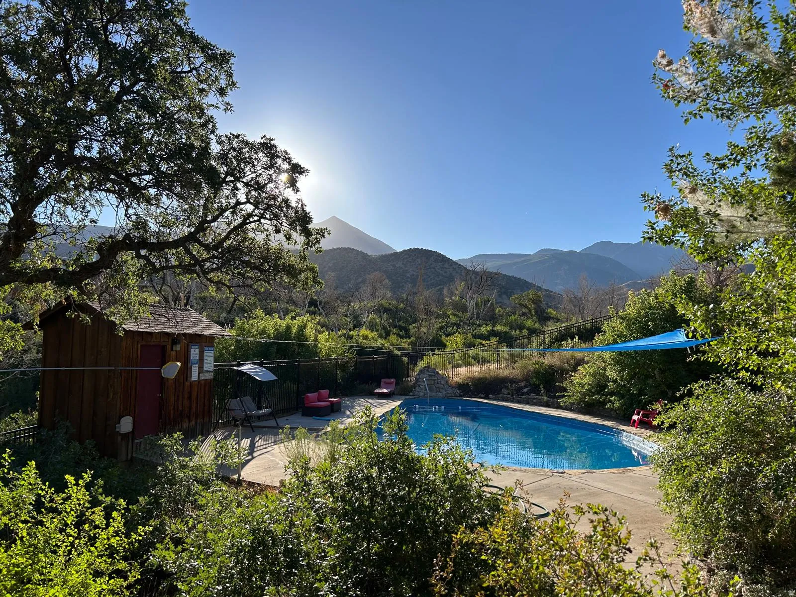 View of swimming pool with patio surround, a mountain view, and a storage shed