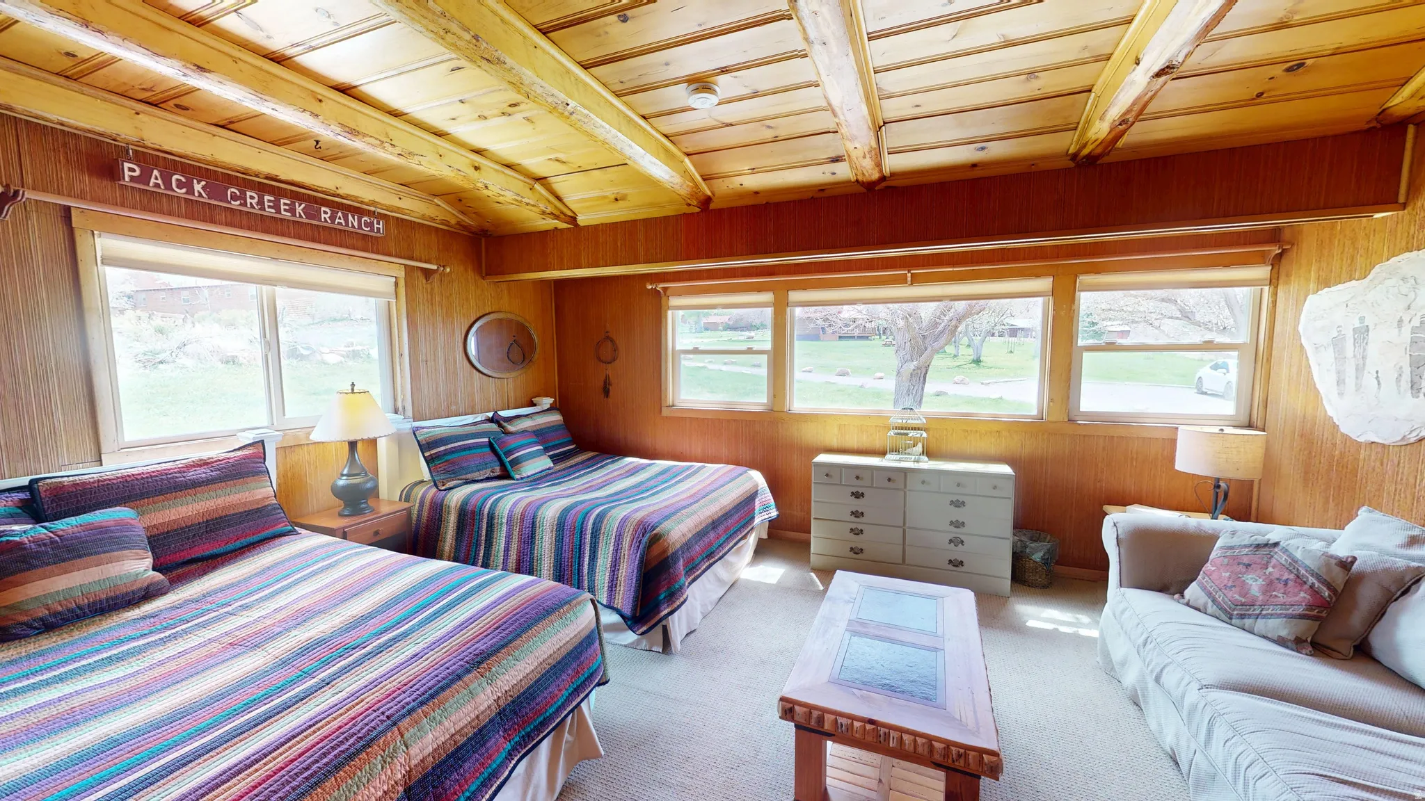 Bedroom with multiple windows, wooden walls, light carpet, and wooden ceiling