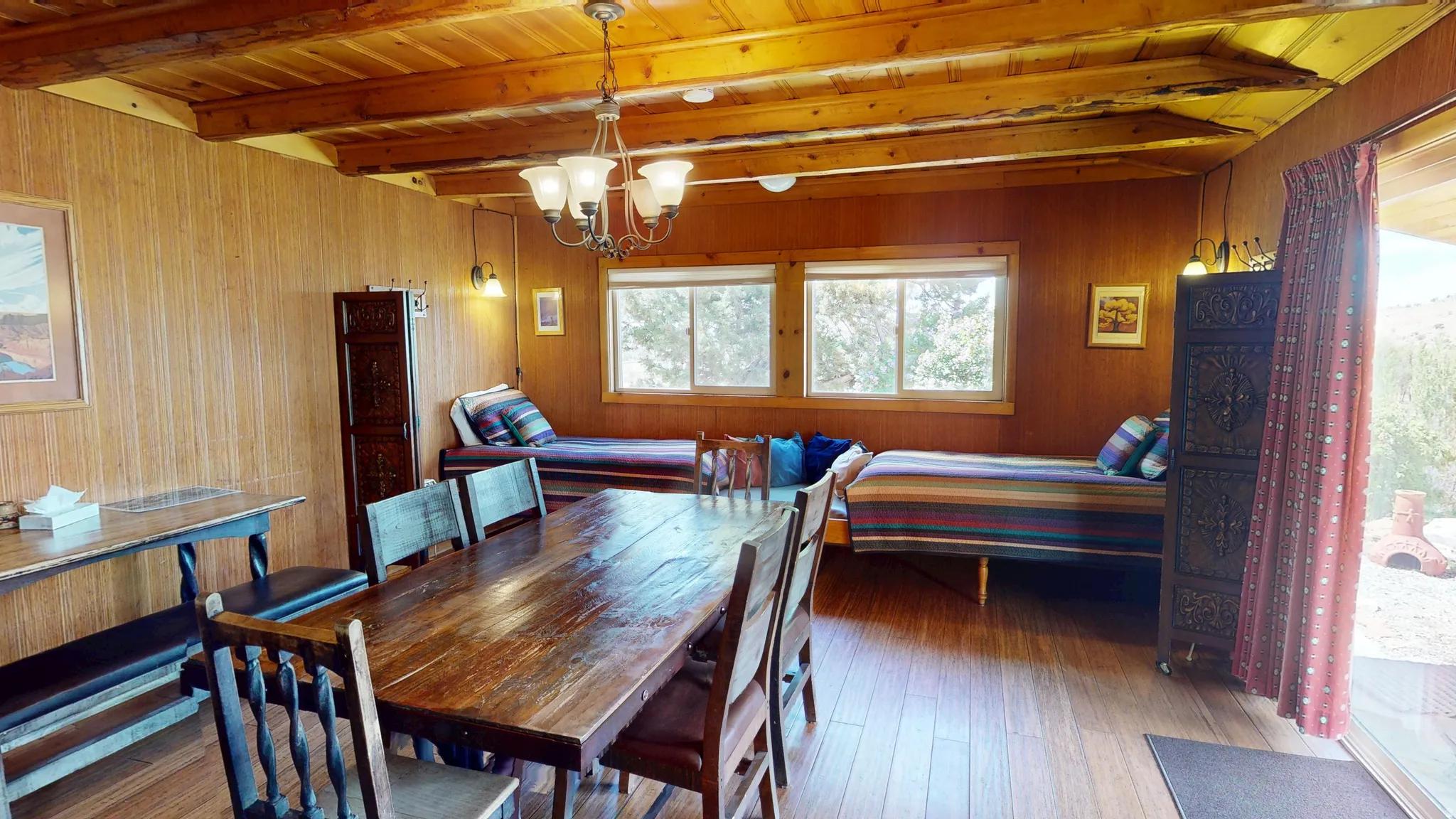 Dining space featuring suspended lighting, wood-type flooring, a wood ceiling with exposed beams, and wooden walls