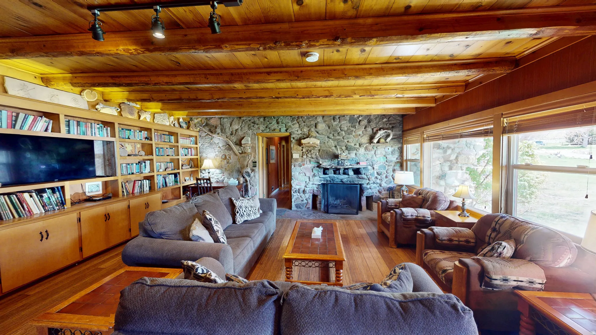 Living room featuring a fireplace, hardwood / wood-style flooring, a wood ceiling with exposed beams, and rail lighting