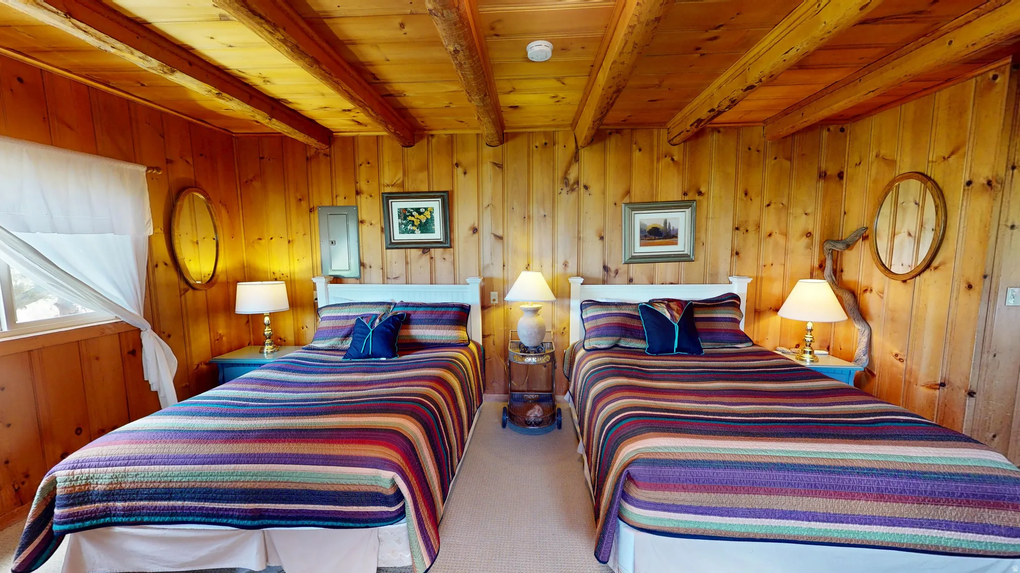 Carpeted bedroom with electric panel, a wooden ceiling with exposed beams, and wooden walls