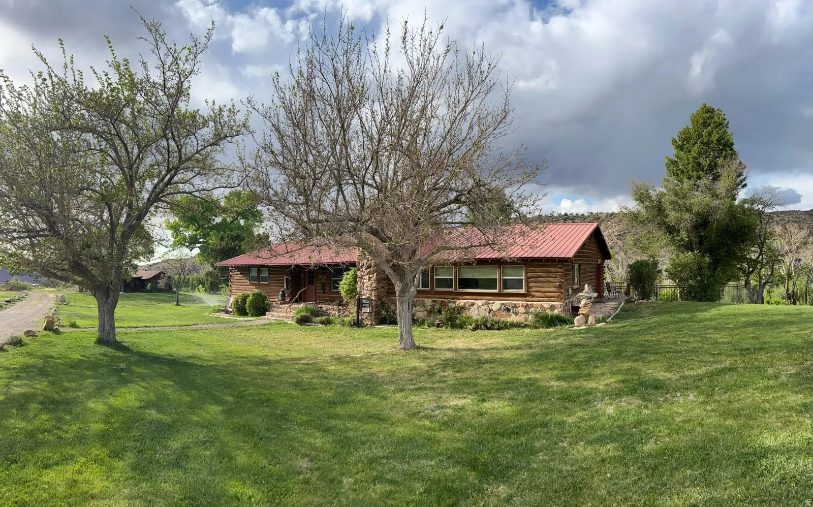 View of front facade with a front lawn, log exterior, and a metal roof