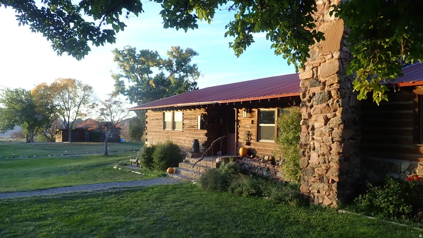 View of front of home with a metal roof, a front yard, and stone siding