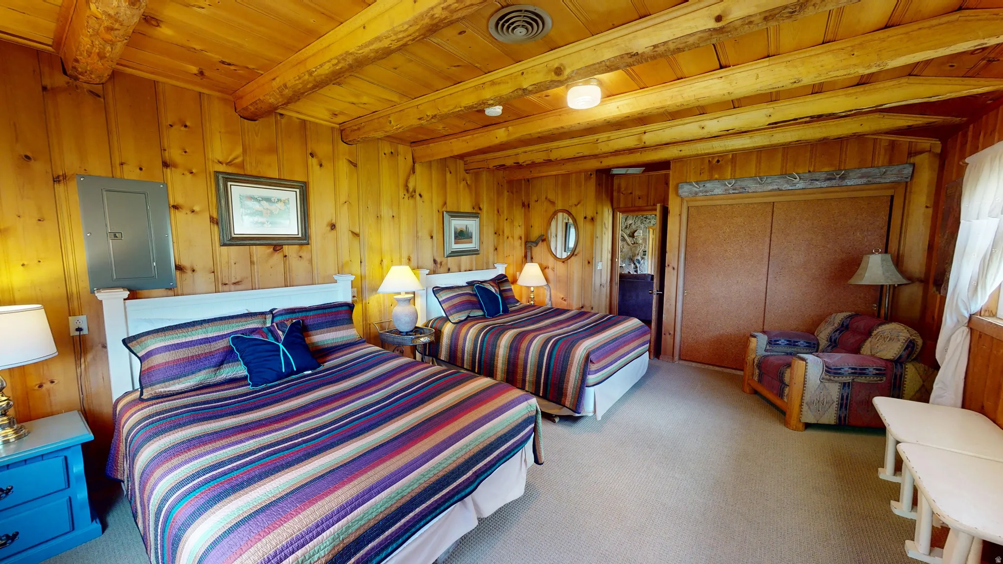 Bedroom featuring electric panel, a wooden ceiling with exposed beams, light carpet, and wood walls