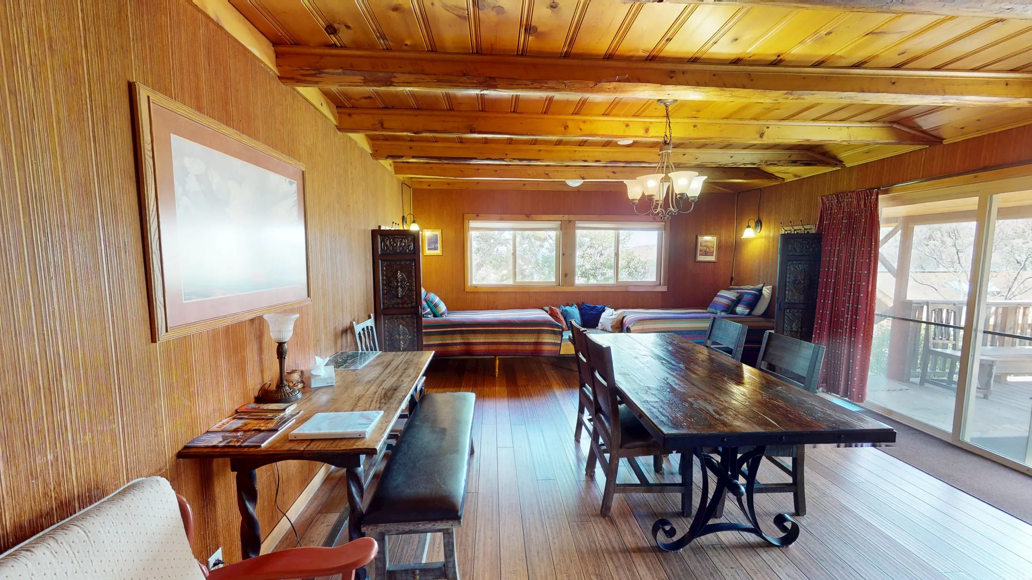Dining space with hanging lights, wood walls, a wood ceiling with exposed beams, and dark wood finished floors
