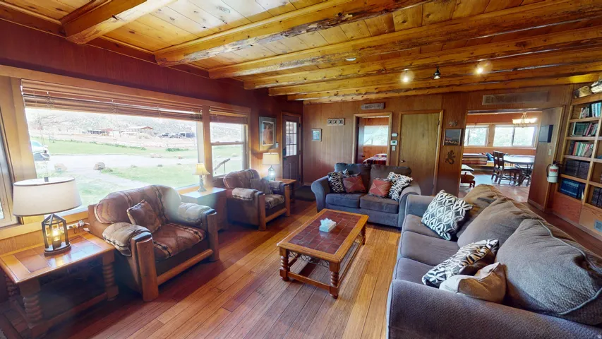 Living room with hardwood / wood-style floors, a wooden ceiling with exposed beams, and wooden walls