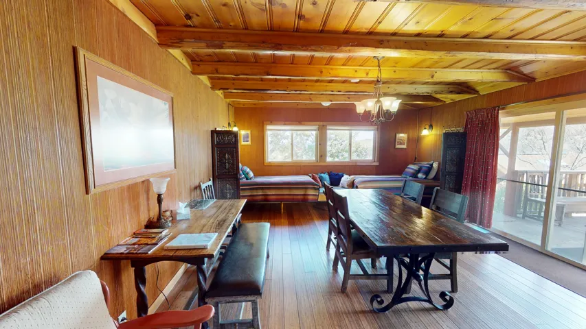 Dining space with hanging lights, wood walls, a wood ceiling with exposed beams, and dark wood finished floors