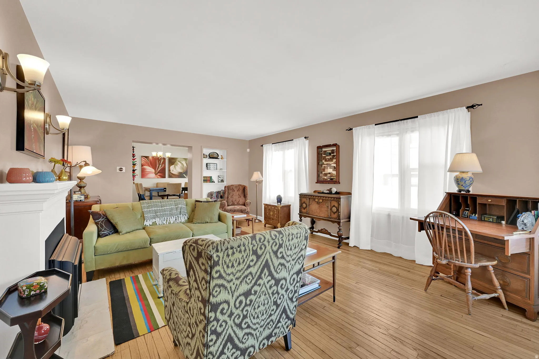 Living room with a gas log fireplace, original wood wood floors, abundant light, and high ceilings