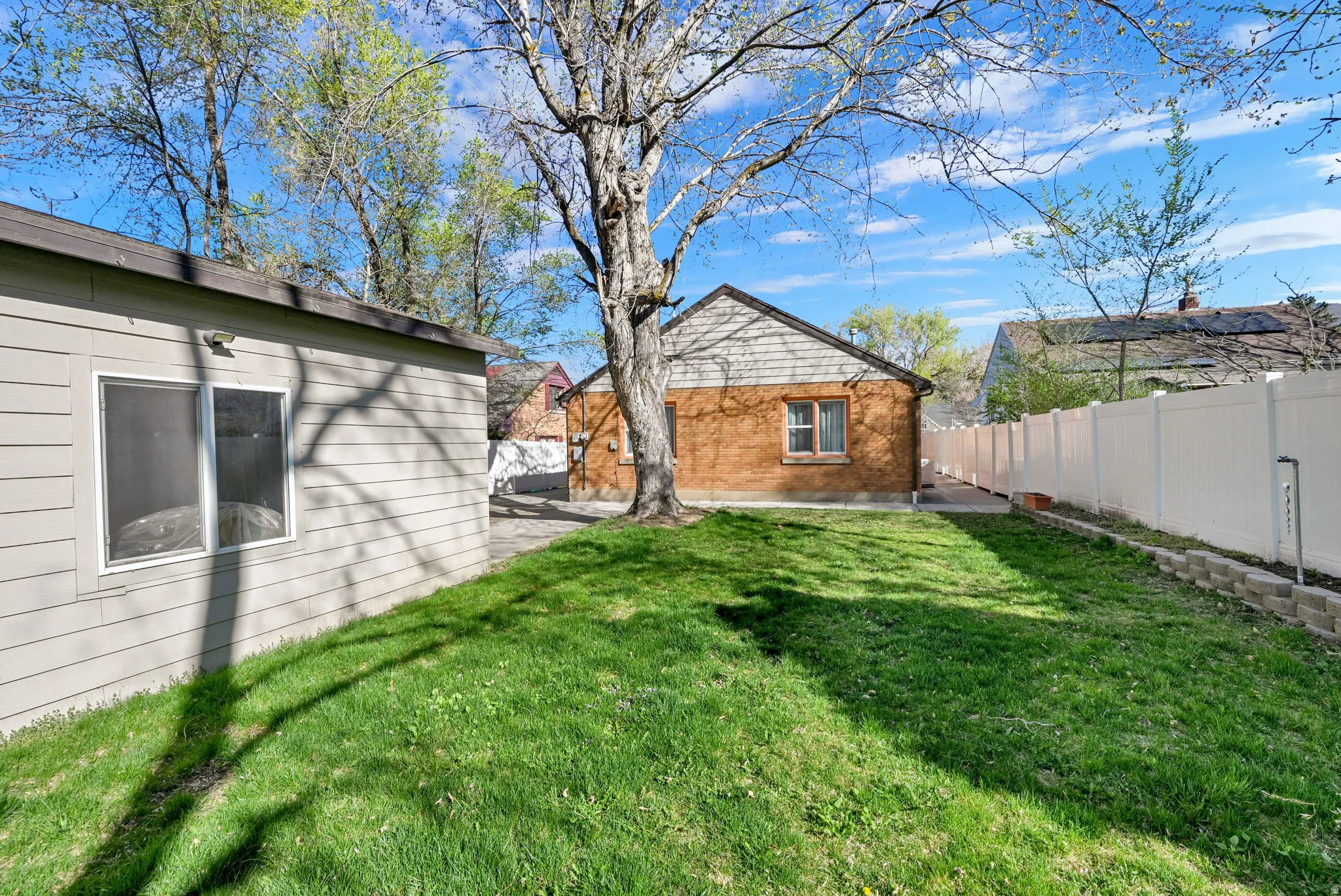 Rear view of property with a patio area, mature trees, and nearly-full fencing