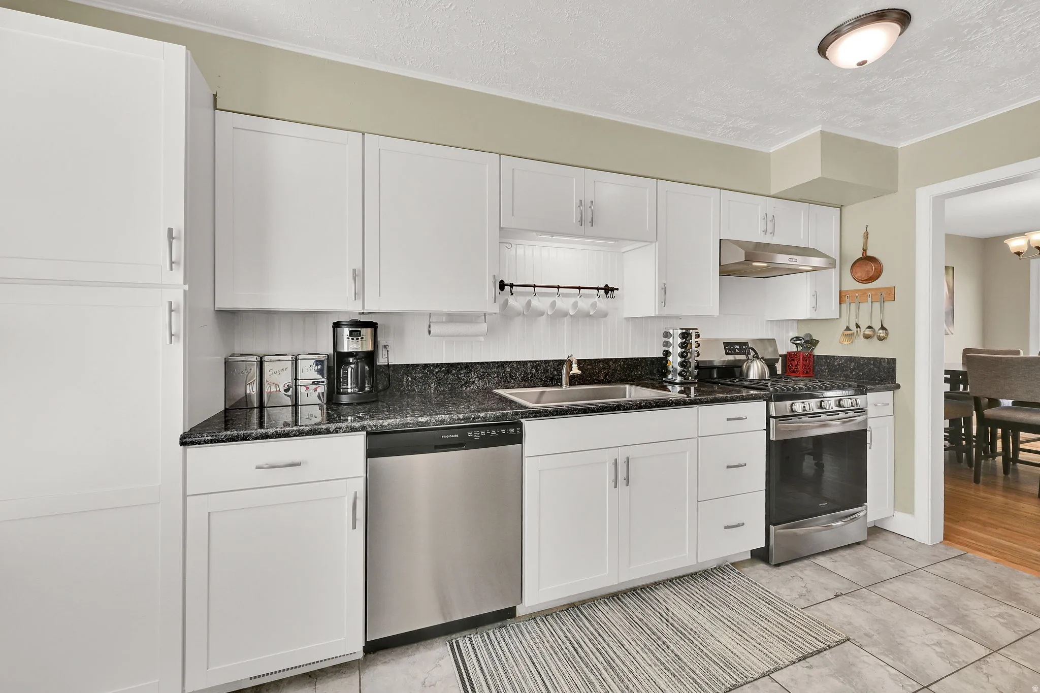 Kitchen featuring stainless steel appliances, updated white cabinetry, and granite counters.
