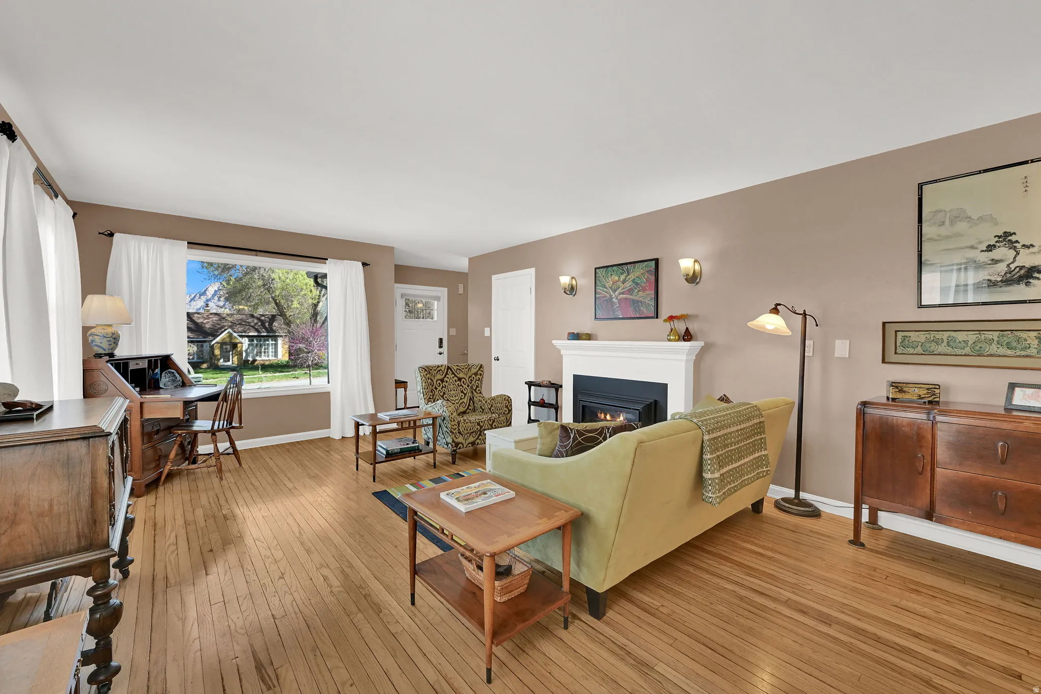 Living room with a gas log fireplace, original wood wood floors, abundant light, and large picture window
