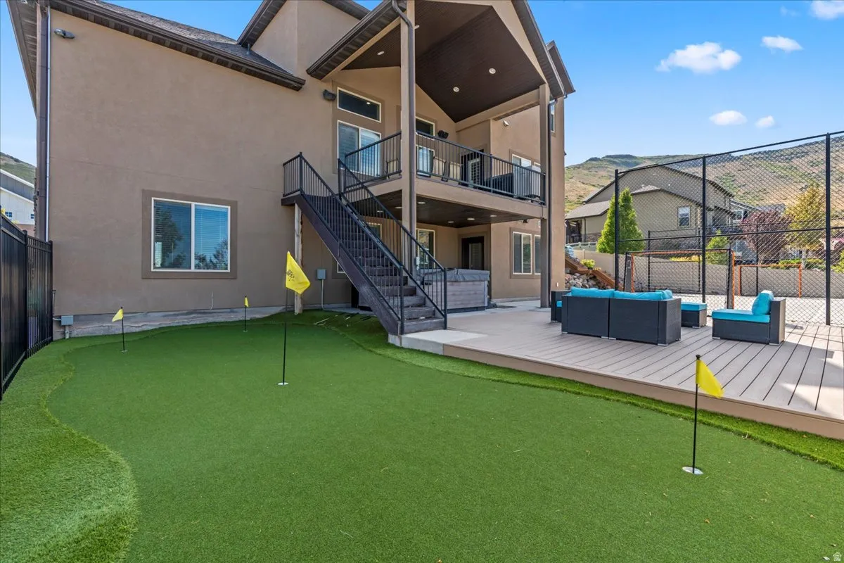 Back of property featuring a putting area, stucco siding, outdoor furniture, and a deck