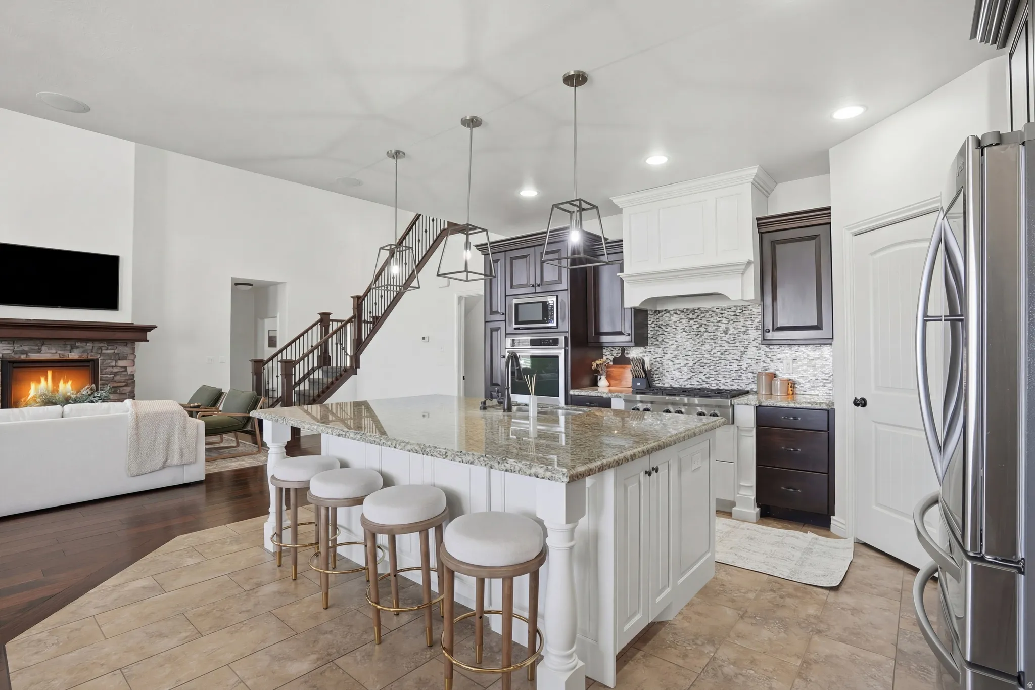 Two tone kitchen featuring two tone color scheme, a kitchen bar, light stone counters, stainless steel appliances, and open floor plan
