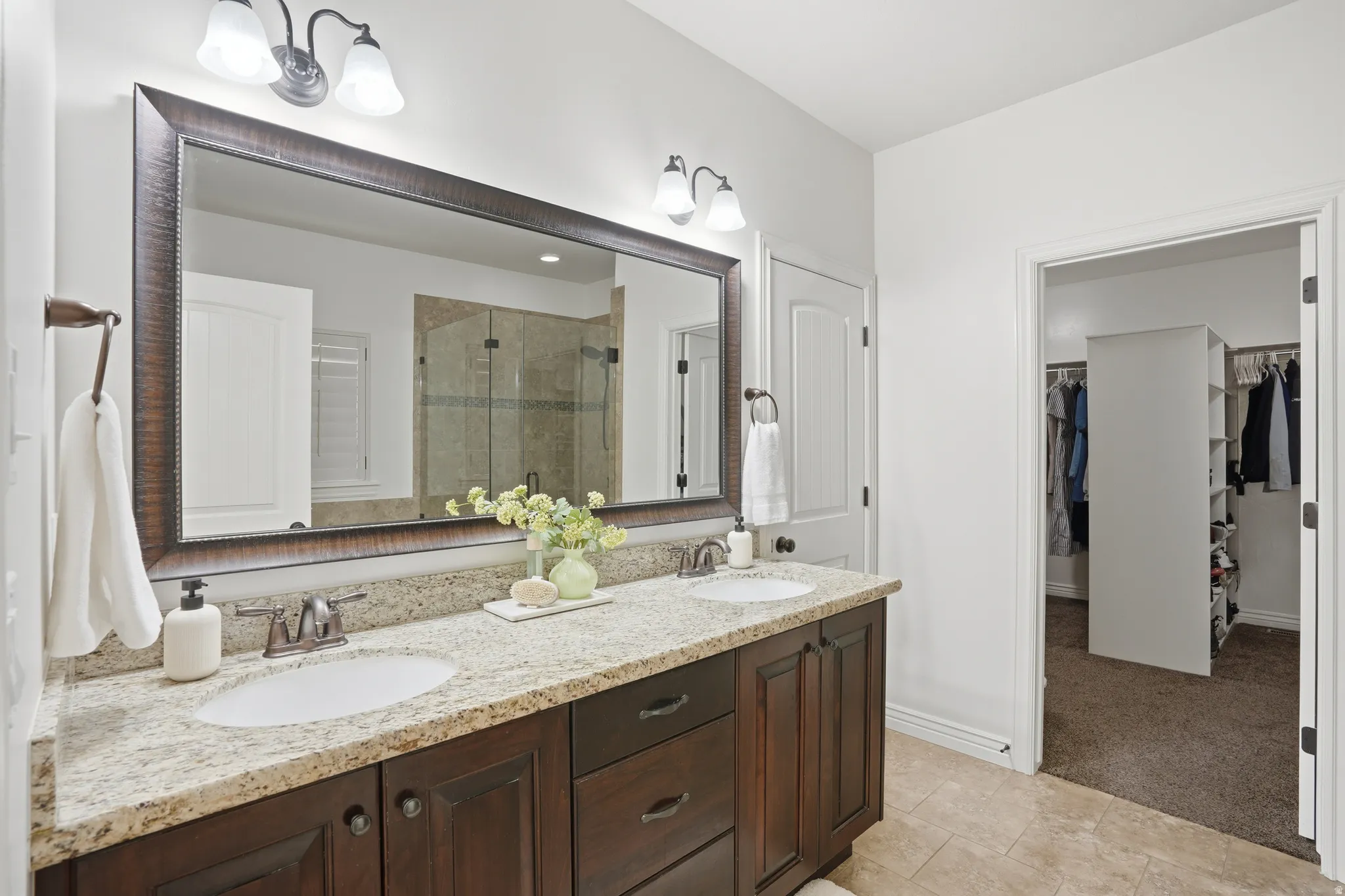 Full bath featuring double vanity, a shower stall, a walk in closet, and light colored carpet