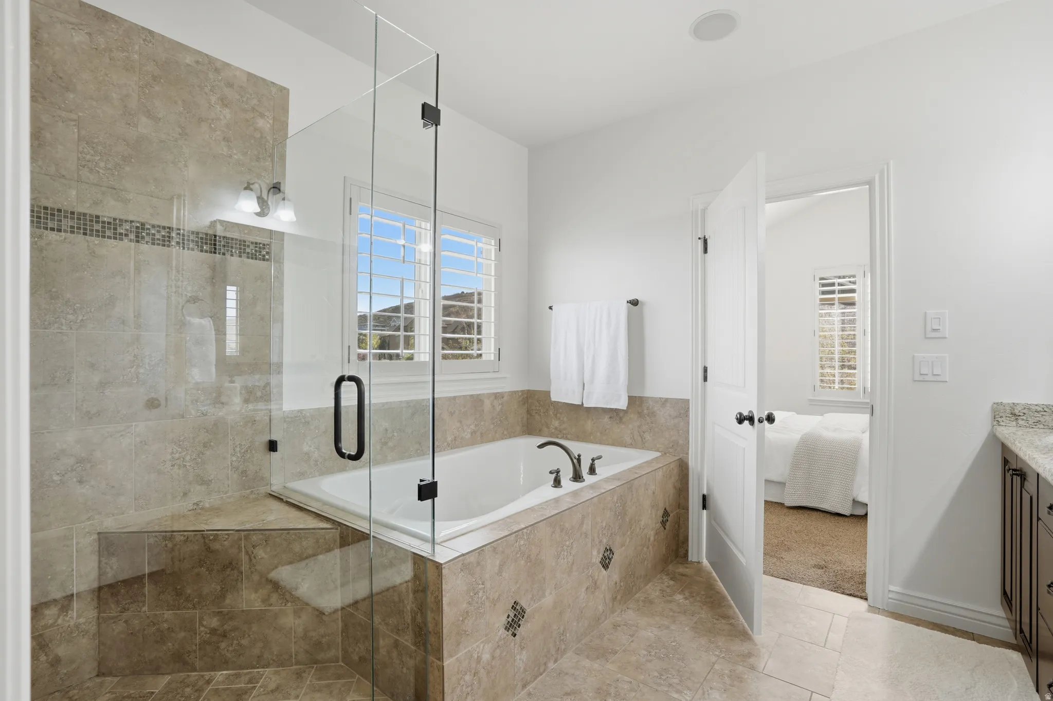 Ensuite bathroom featuring vanity, a stall shower, light tile patterned flooring, a garden tub, and light colored carpet