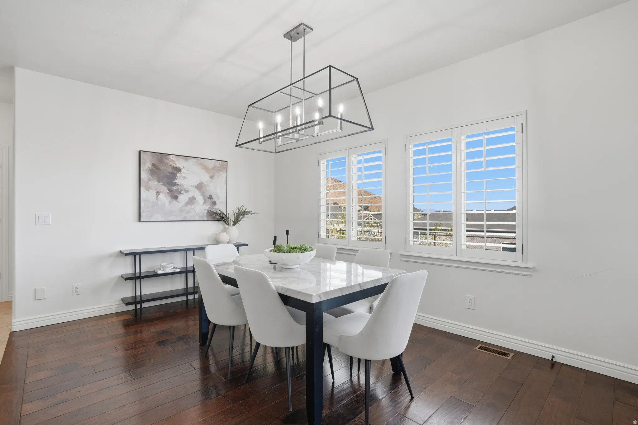 Dining space with dark wood finished floors and suspended lighting