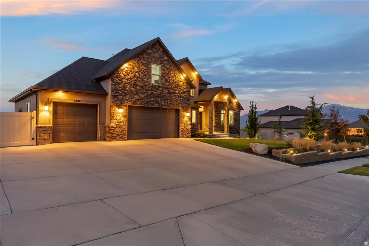Craftsman inspired home with concrete driveway, a garage, stone siding, a front yard, and a gate