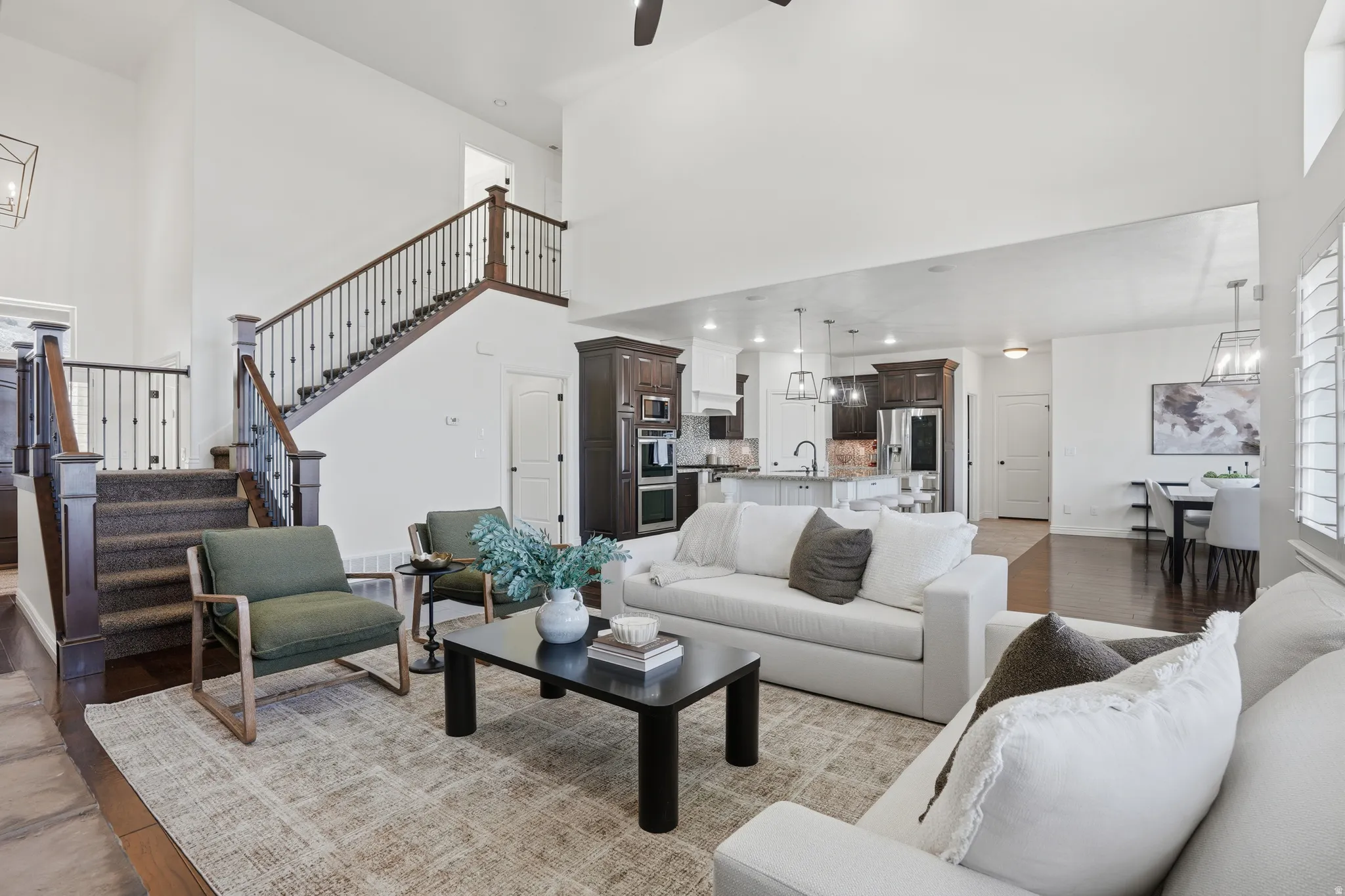 Living area with a chandelier, light wood-style floors, a high ceiling, and a ceiling fan