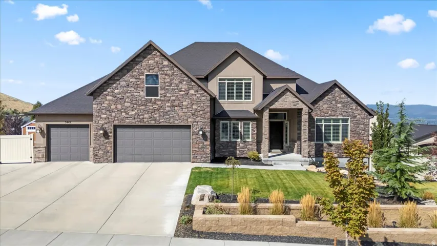 Craftsman-style home featuring concrete driveway, a front lawn, roof with shingles, a mountain view, and an attached garage