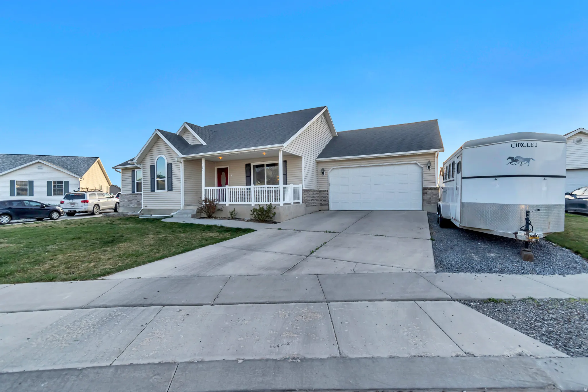 View of front of home with a porch, driveway, a garage, and a front lawn