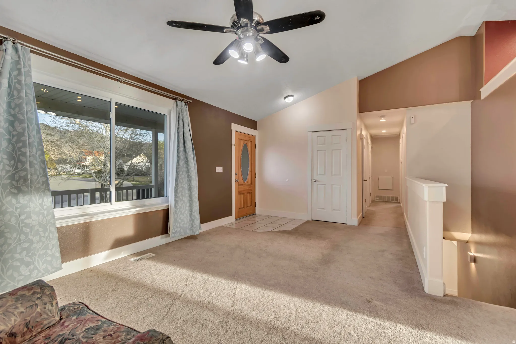Unfurnished bedroom with lofted ceiling, light colored carpet, and a ceiling fan