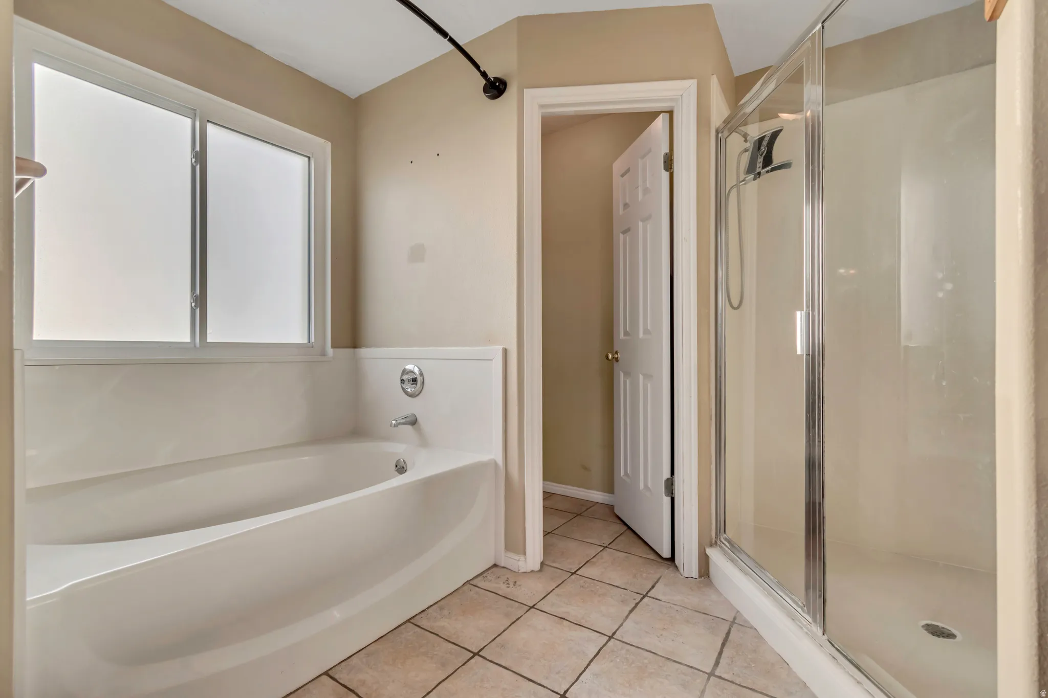 Bathroom featuring a stall shower, light tile patterned flooring, and a bath