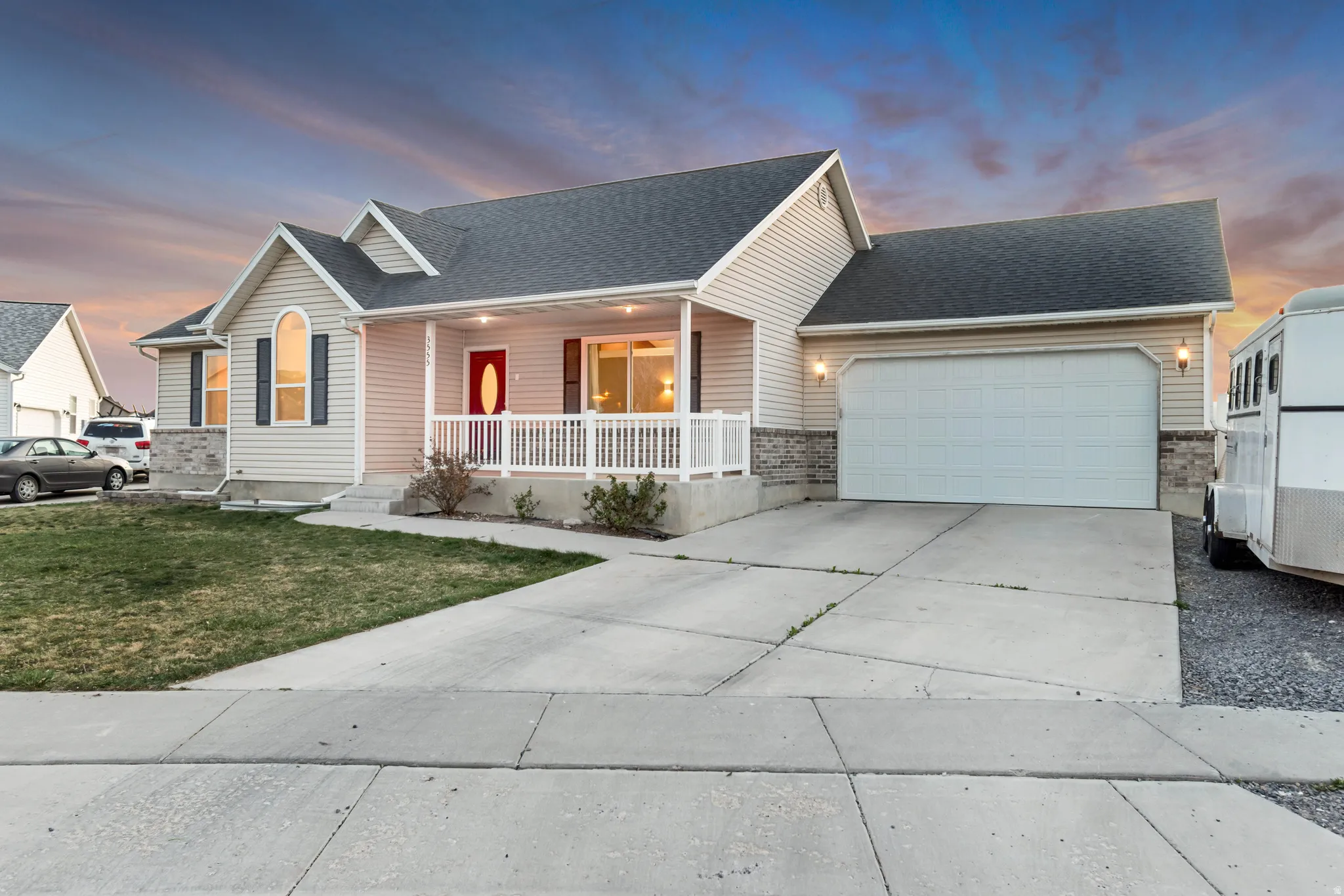 View of front facade with covered porch, an attached garage, a shingled roof, driveway, and a front lawn